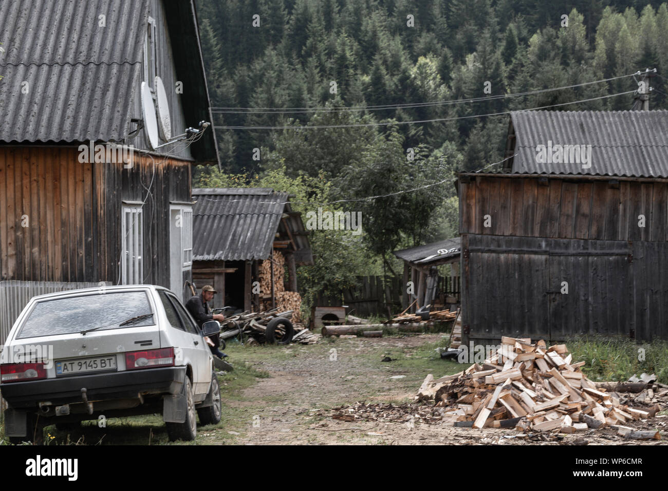 Alte Holzhäuser in der Ukraine, Karpaty. Weiß altes Auto Lada und betrunkenen Mann Stockfoto