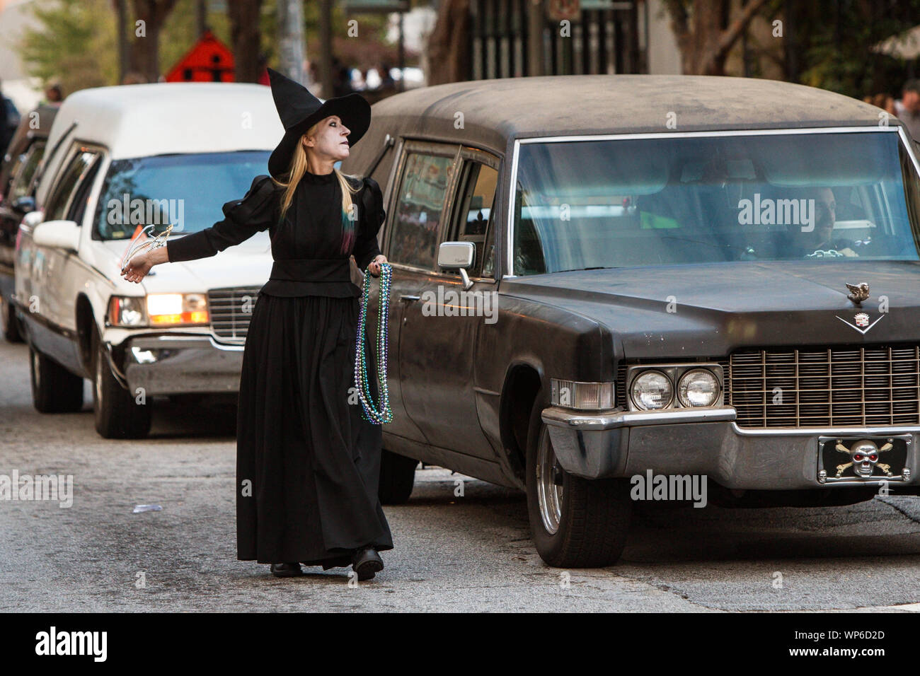 Eine Frau in einer schwarzen Hexe Kostüm Spaziergänge neben Leichenwagen Perlen am Haints und Heiligen Halloween Parade am 27. Oktober 2018 zu werfen. Stockfoto
