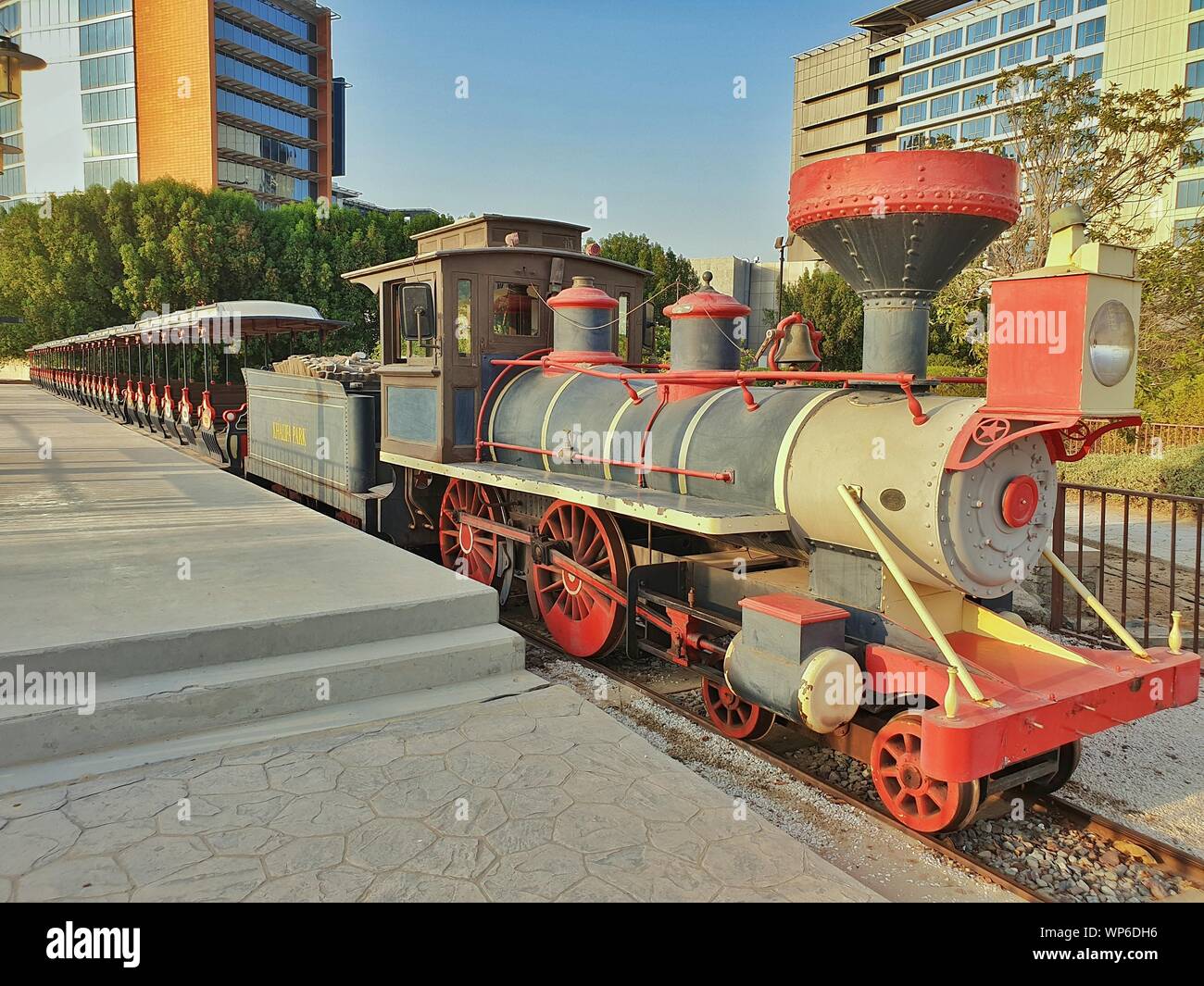 Fahrt MIT DEM ZUG IN EINEM PARK MIT LANGEN DREHGESTELLE UND FAHRGASTRAUM DAMPFLOK BATTERIEBETRIEBEN VOR EINER PLATTFORM Stockfoto