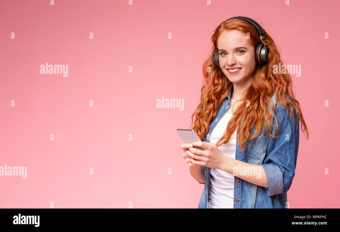 Fröhliches Mädchen mit roten Haaren Musik online auf dem Smartphone Stockfoto