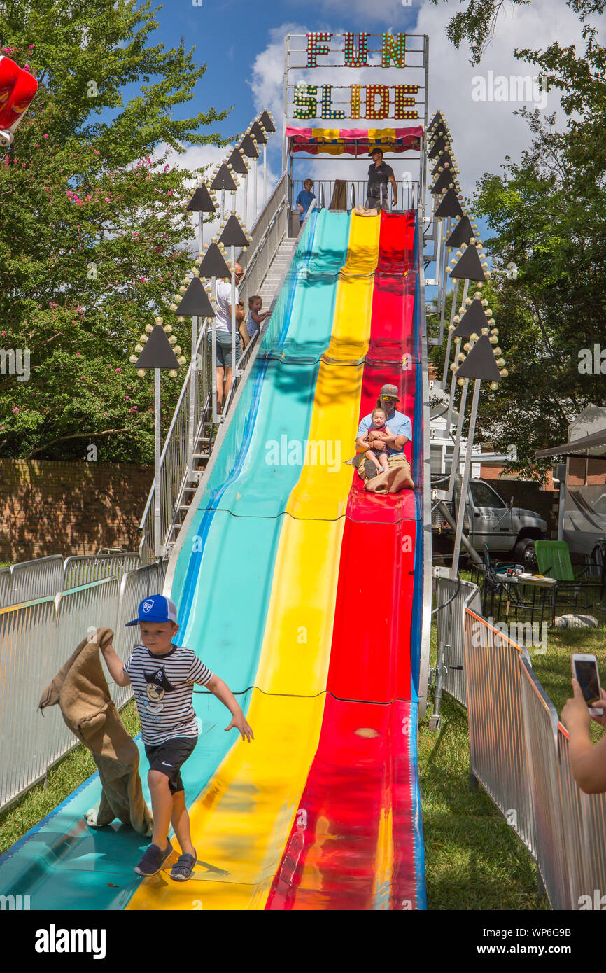 MATTHEWS, NC (USA) - September 2, 2019: Eltern und Kinder genießen eine riesige Karneval Folie an der jährlichen 'Matthews Lebendig" Gemeinschaft Festival. Stockfoto