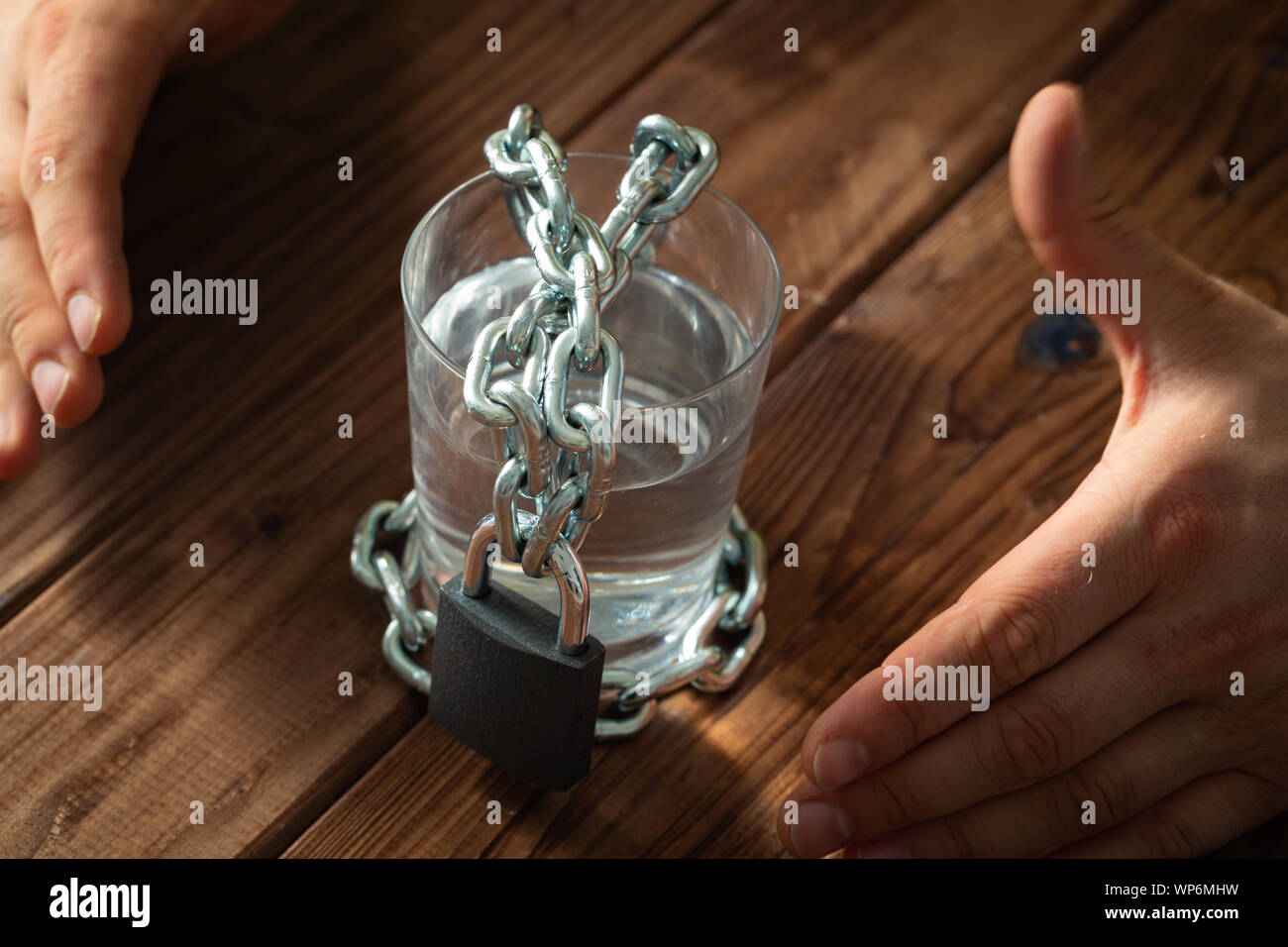 Ein Glas Wasser in einer Kette gewickelt und mit einem Vorhängeschloss. Das Konzept des Problem der kleinen Trinkwasser in der Welt Stockfoto