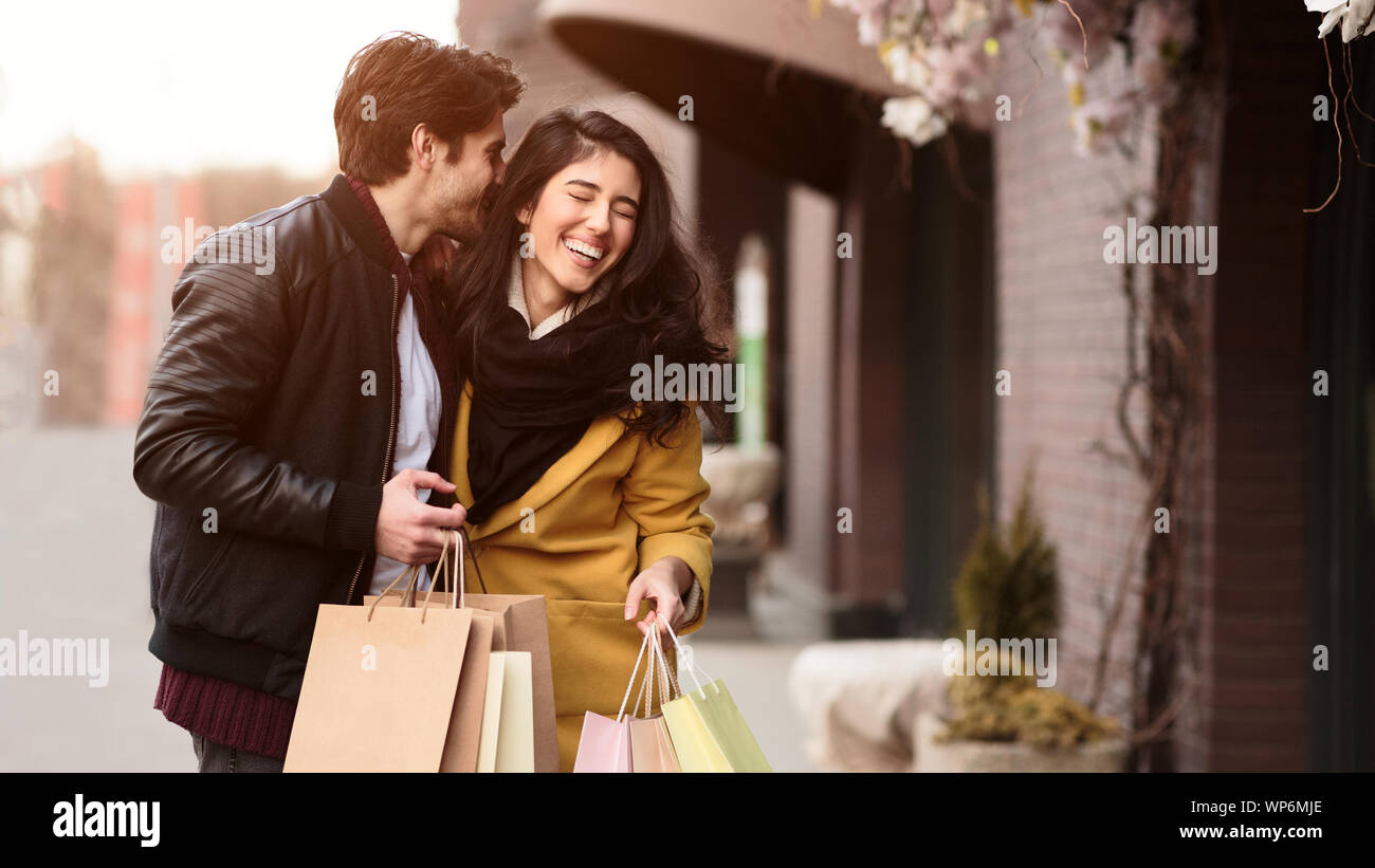 Zusammen einkaufen. Mann in der Frau Ohr flüstern Stockfoto
