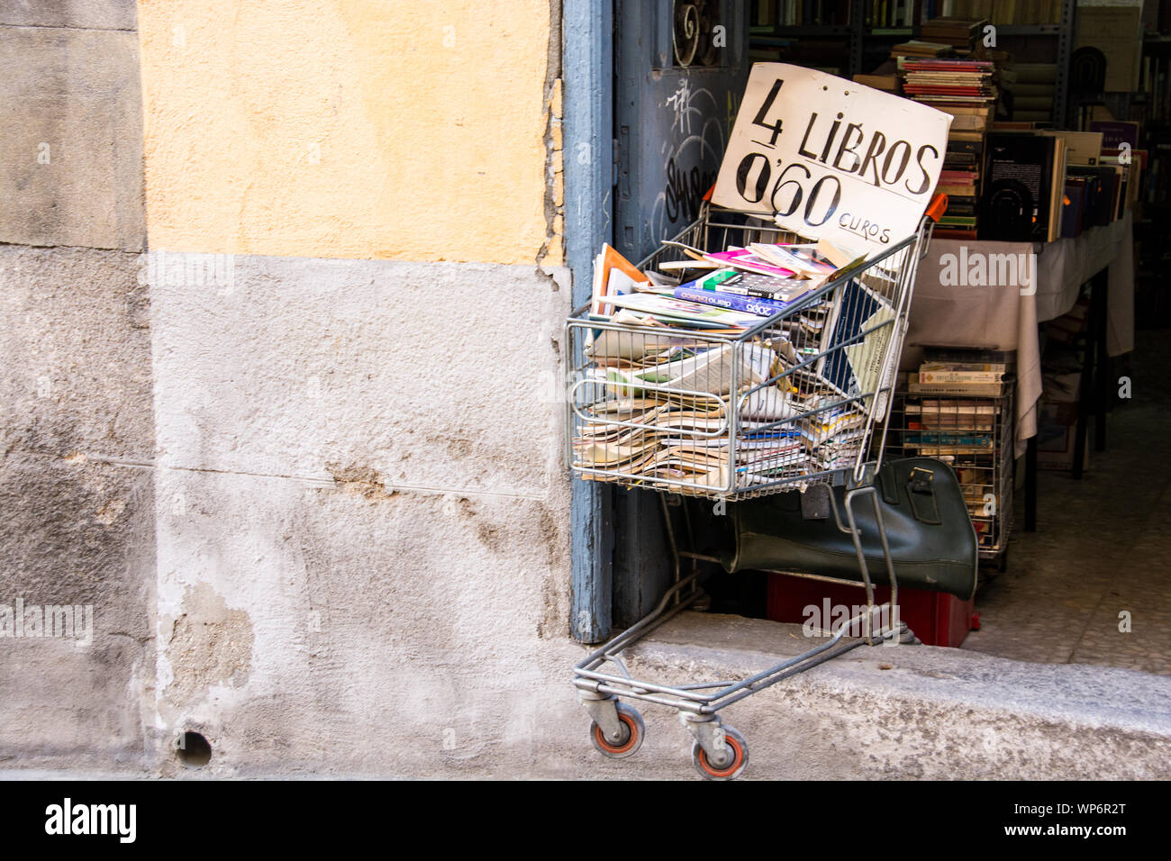 Ein Einkaufswagen am Eingang eines Buchladens in Toledo, Spanien, gefüllt bis zum Rand mit Büchern und anderen Zeitschriften. Stockfoto