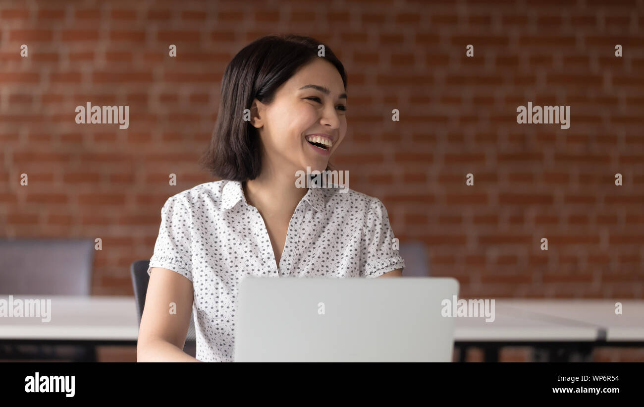 Fröhlich Asian Business Frau im Gespräch mit jemand beiseite. Stockfoto