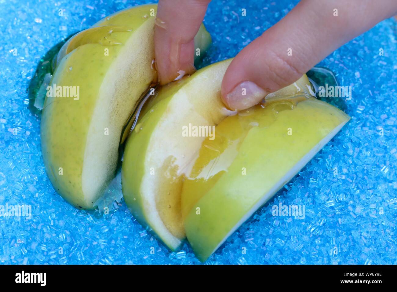 Kleine Finger greifen Apfelscheiben eingetaucht in Honig für das Jüdische Neue Jahr Stockfoto