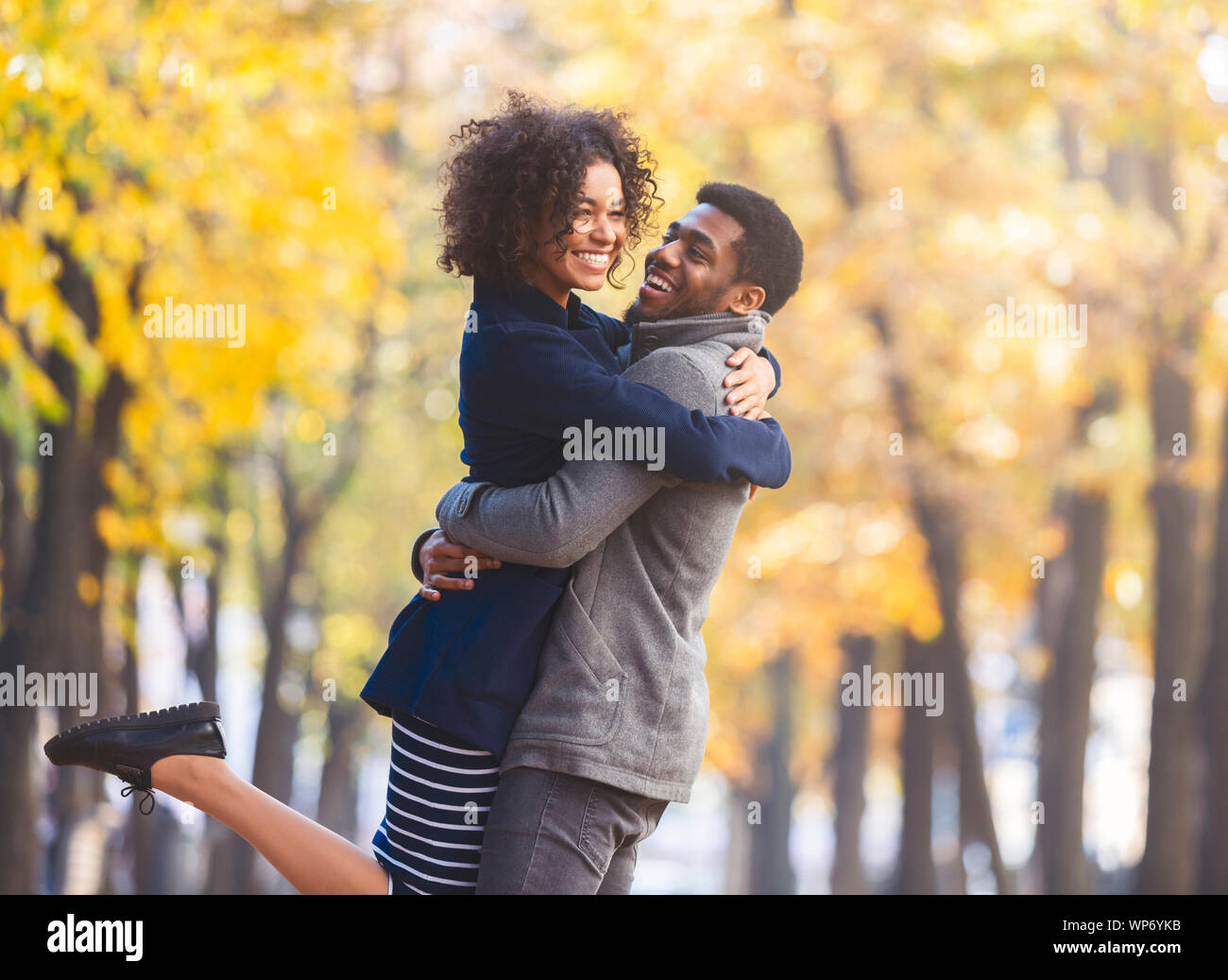 Hübscher junger Mann seine Freundin anheben, während Sie umarmt ihn Stockfoto