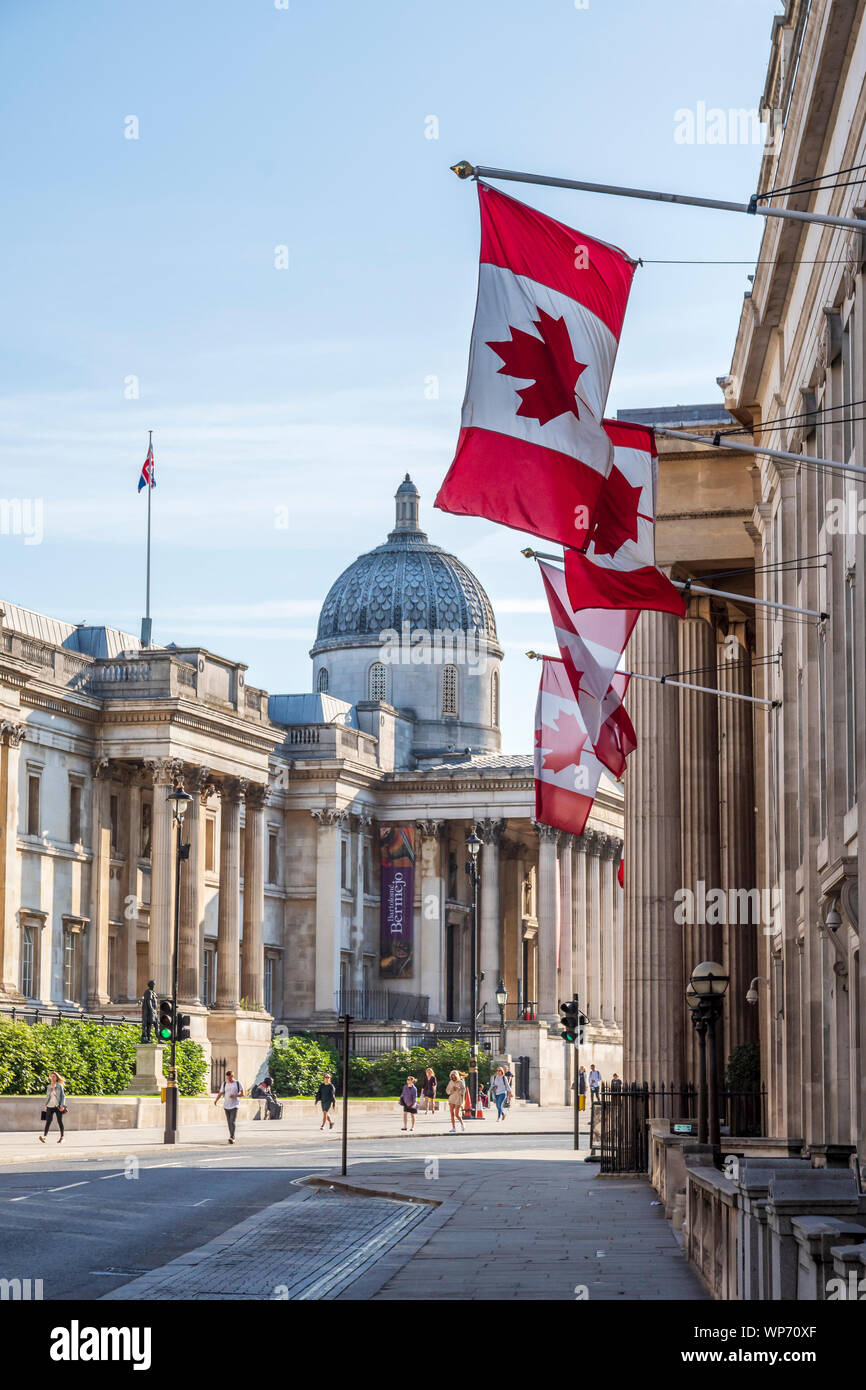 Kanadische Fahnen an den Kanada hohe Kommission Gebäude in London hängend, mit der Nationalen Galerie hinter Stockfoto