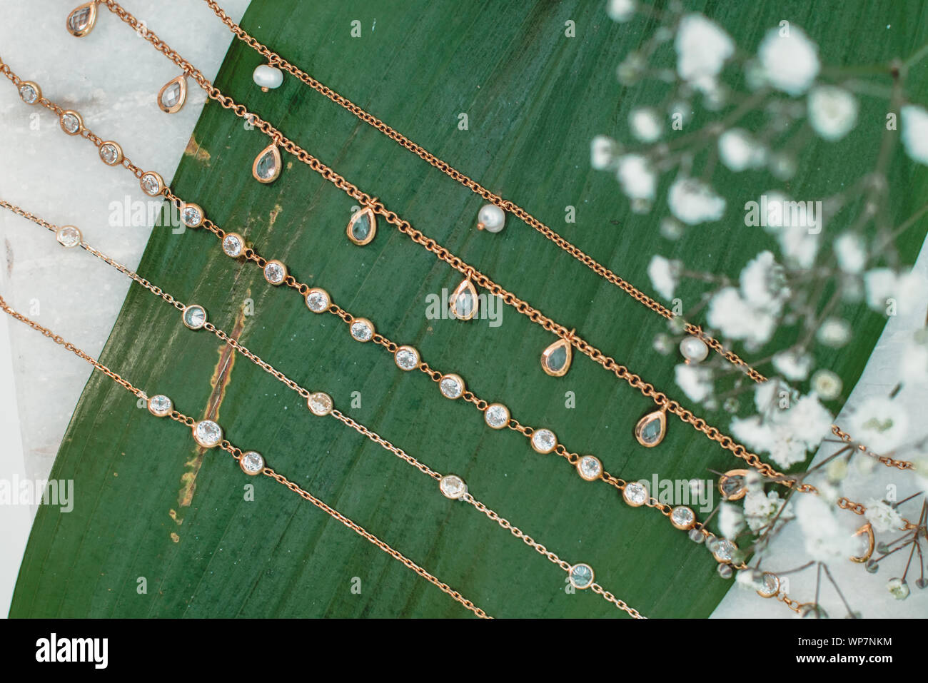 Luxus Closeup auf viele Halsketten, eine grüne Blume und ein grünes Blatt Stockfoto