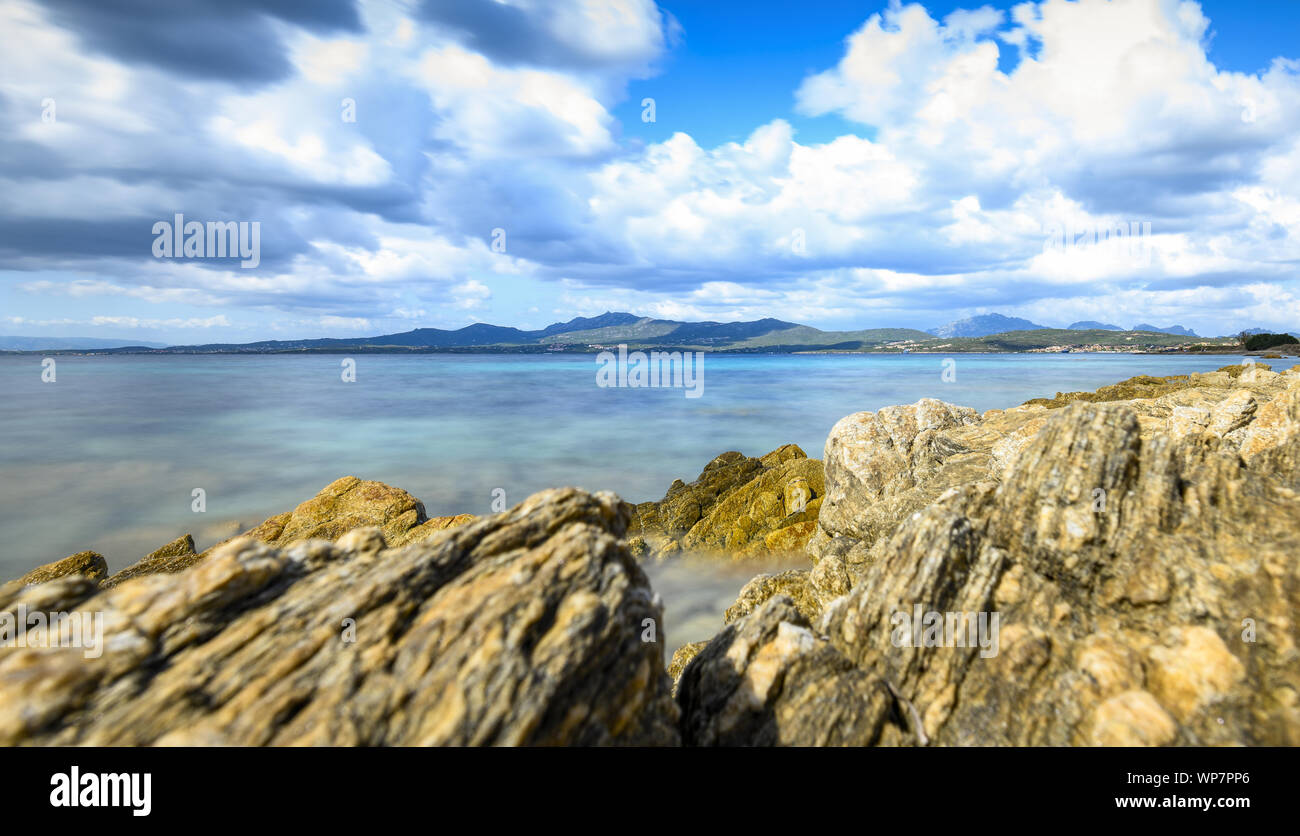 (Selektive Fokus) Schönen Meereslandschaft mit einem bewölkten Himmel, Türkis (silky) Wasser und einige Felsformationen im Vordergrund. Costa Smeralda, Sardinien. Stockfoto