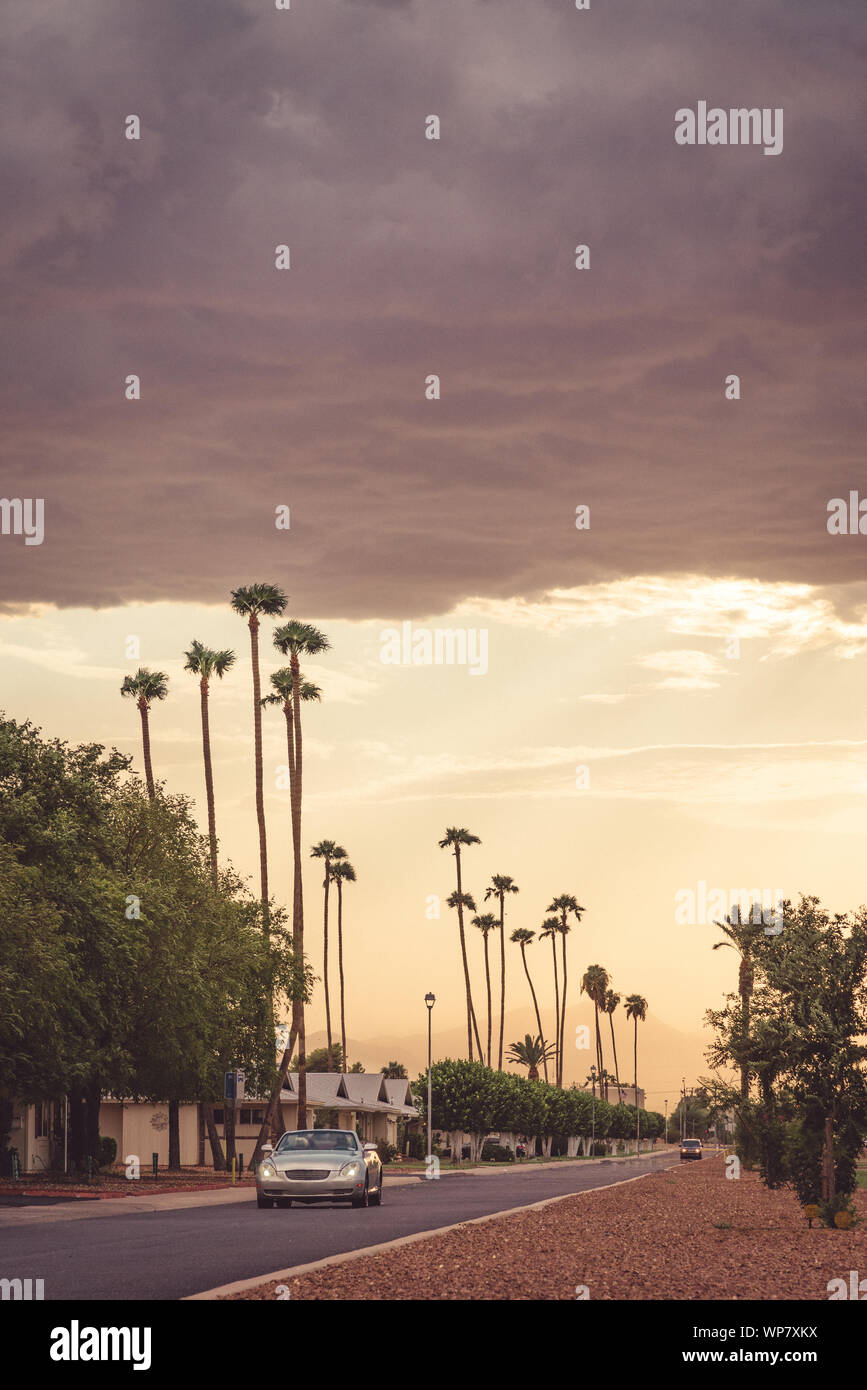 Analoge Fotografie von einem Cabrio fahren auf Peoria Avenue unter einem stürmischen Nachmittag Himmel in Sun City, Arizona. Stockfoto