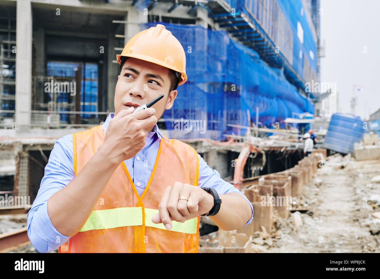 Portrait von Runzelte ernst Auftragnehmer mit walkie-talkie beim Stehen an der Baustelle des neuen Gebäudes Stockfoto