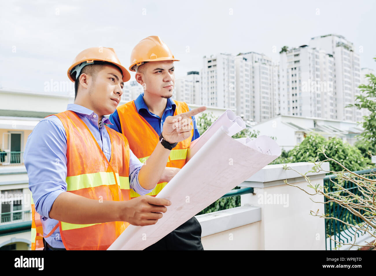 Ernsthafte Bauarbeiter stehen im Freien mit Gebäude blueprint und diskutieren Abfolge von Arbeit, die heute getan werden. Stockfoto