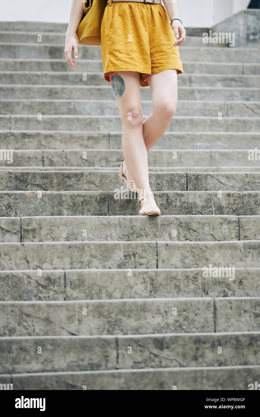 Zugeschnittenes Bild der jungen Frau in Senf Bettwäsche Sommer Shorts zu Fuß die Treppe hinunter Stockfoto