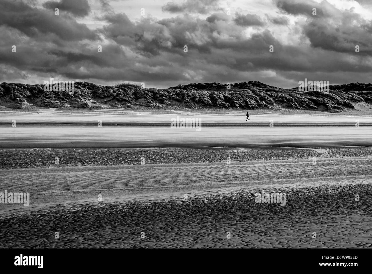 Einzelne Person allein gehen an einem windigen Strand von Bray-Dunes in Frankreich Stockfoto