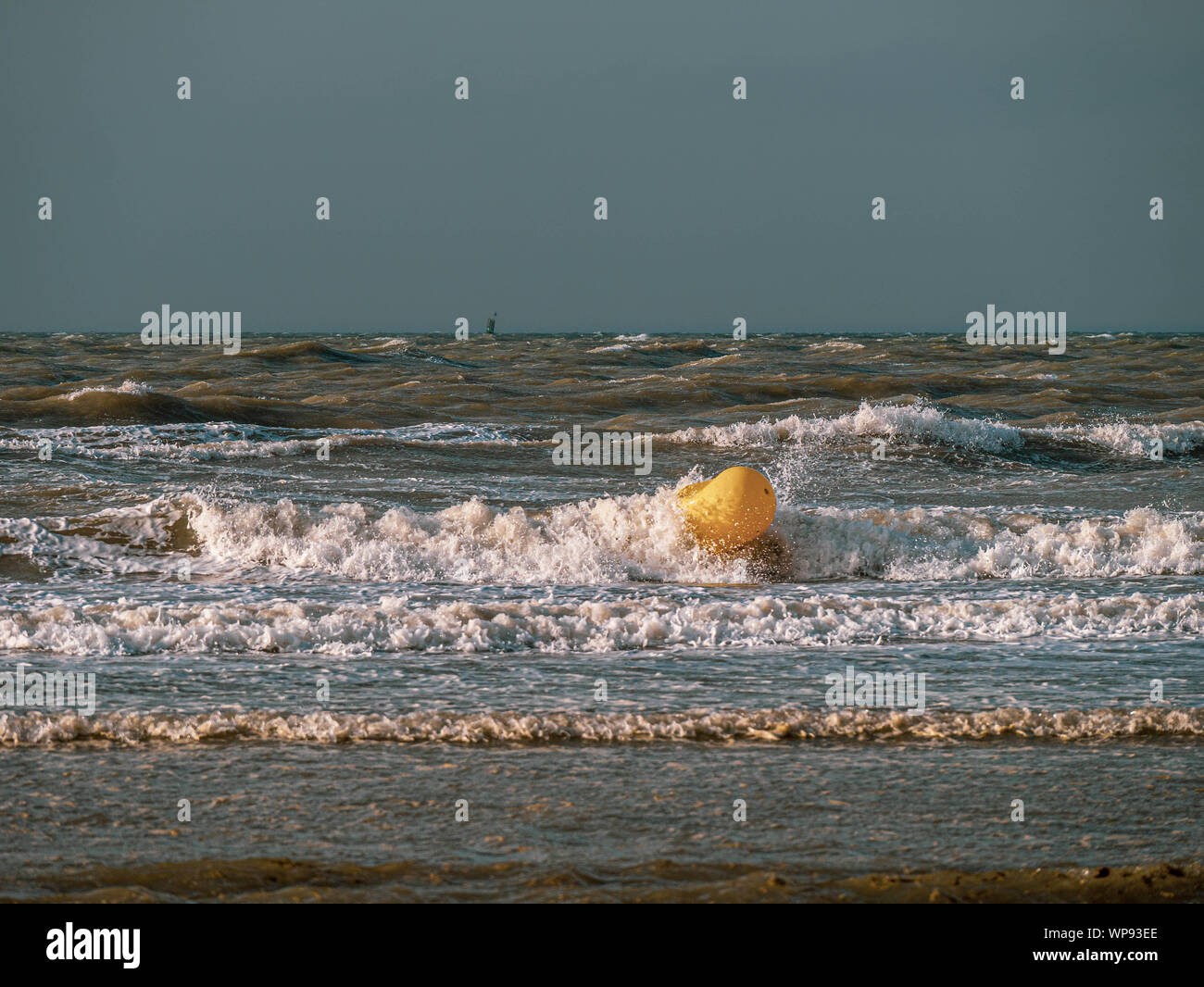 Gelbe Boje bei Ebbe in rauen Gewässern in der Nähe vom Strand Stockfoto