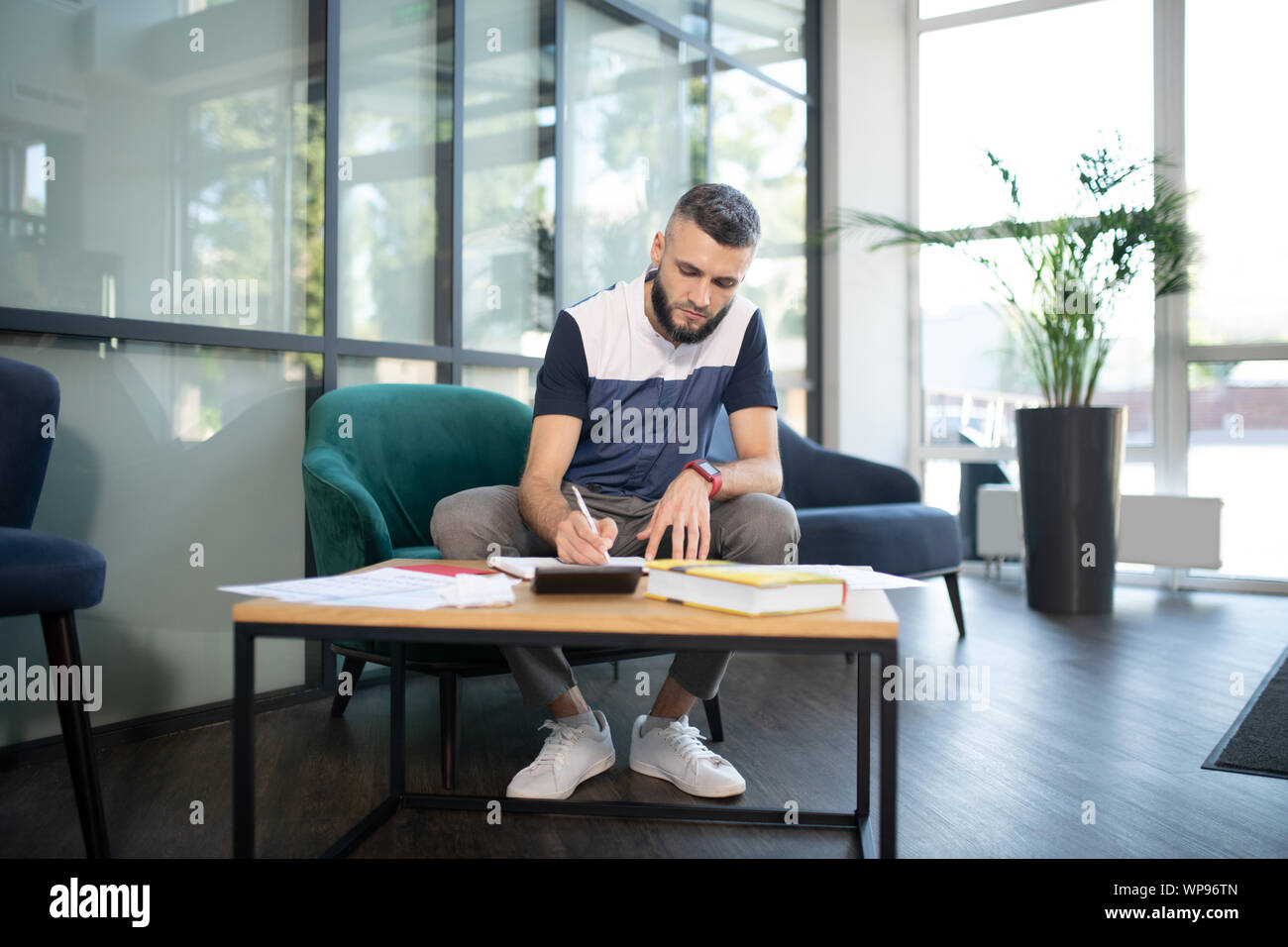 Stilvolle Geschäftsmann sitzt auf einem Sessel und Abfüllung in Dokumenten Stockfoto