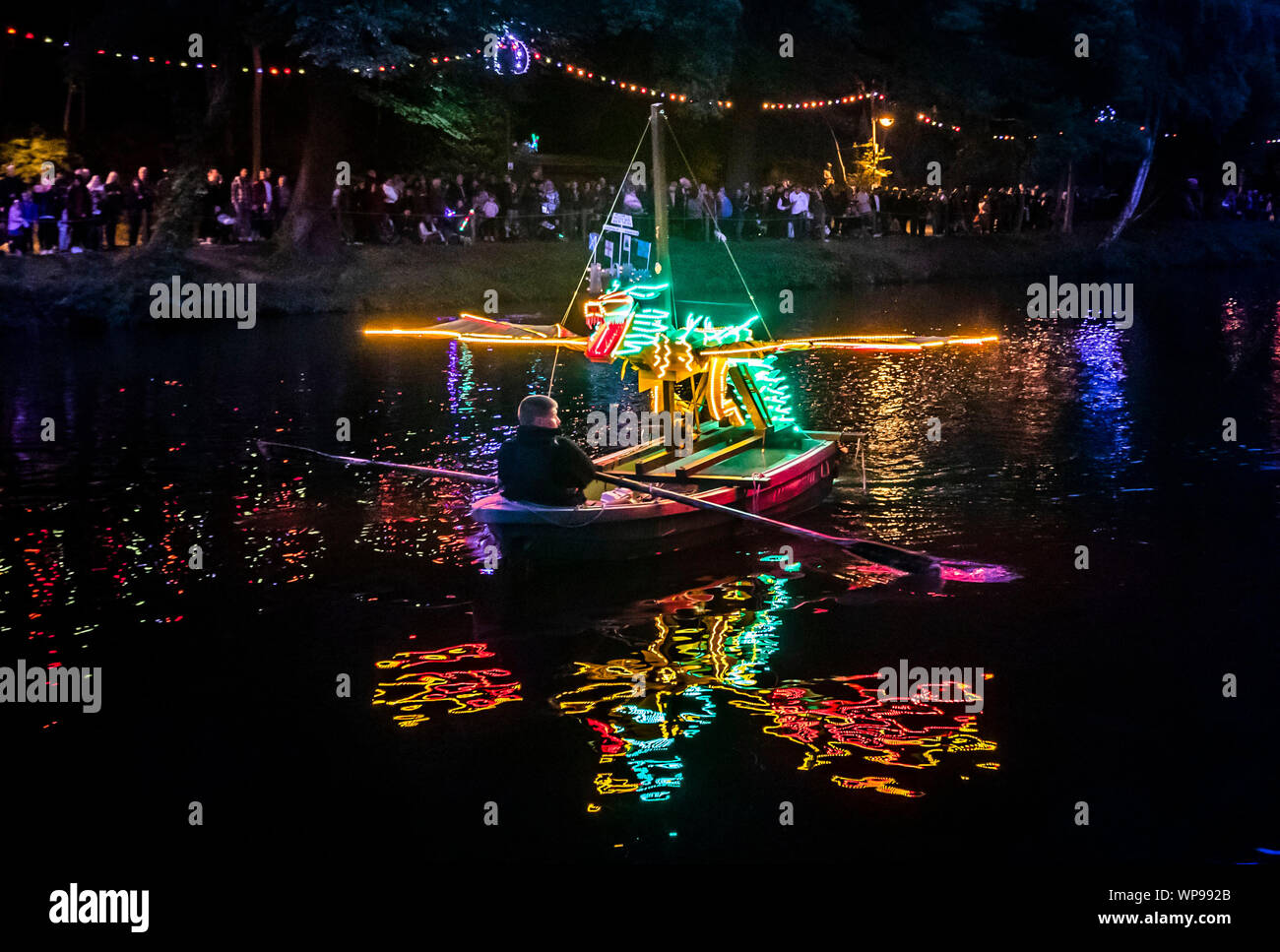 Eine Flotte von hell beleuchteten Booten gerudert sind den Fluss Derwent während der Matlock Bath Illuminationen, in der Peak District, die illuminationen wurden zum ersten Mal Queen Victoria Diamond Jubiläumsfeierlichkeiten im Jahre 1897 zu feiern. Stockfoto