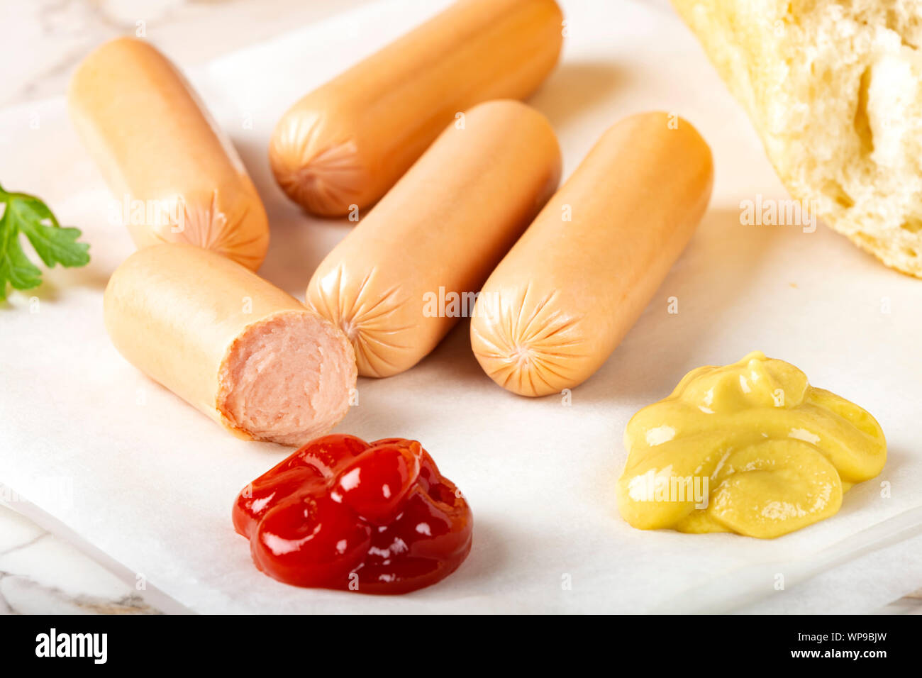 Kleine Würstchen mit Ketchup und Senf und Brot Stockfoto