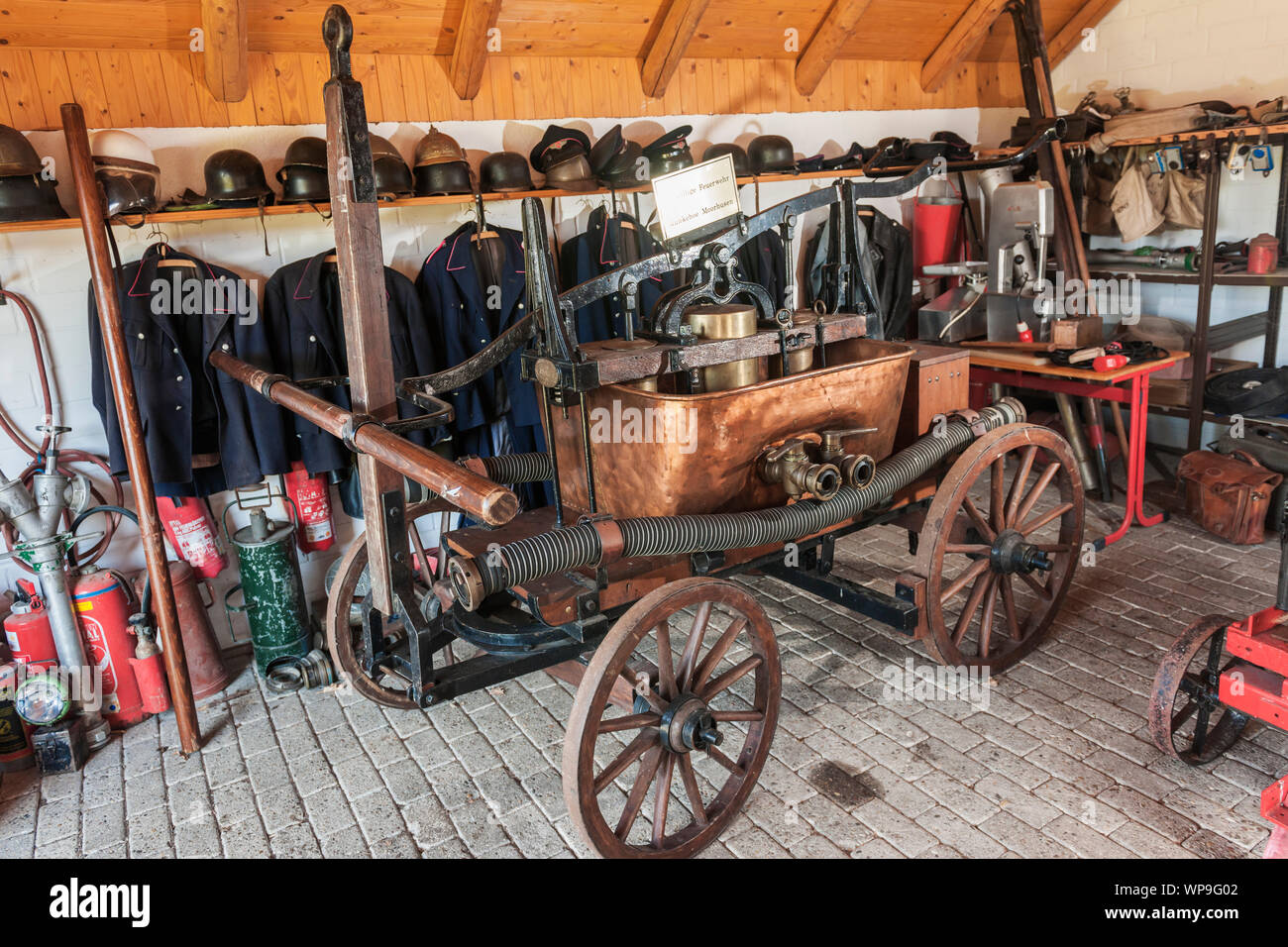 Blick in eine alte Feuerwache mit handbetätigter Feuerwehrautos, alte Uniformen aufgereiht auf die Wände und die verschiedenen Einrichtungen zur Brandbekämpfung. Stockfoto