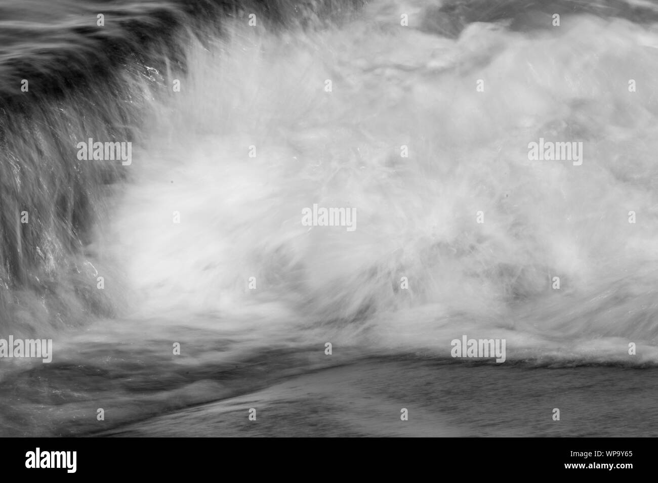 Schwarze und Weiße abstrakte Fotografien einer Meereslandschaft mit starken Rückspülen mit Wasser fließt über eine Flutwelle pool Wand auf einem niedrigen Verschlusszeit - leistungsstark Stockfoto