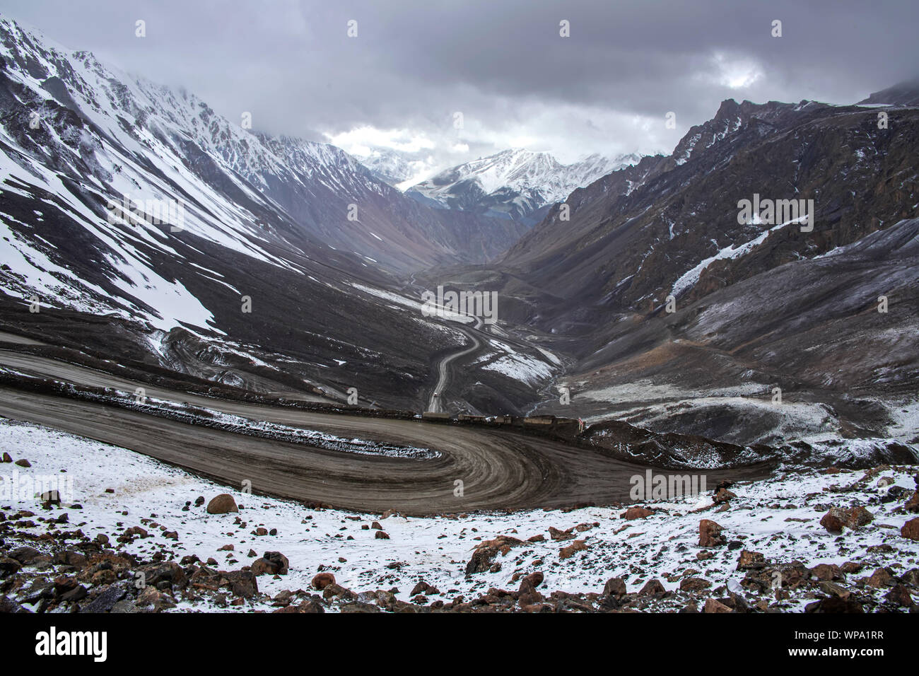 Blick von oben auf eine Serpentine Mountain Road zwischen schneebedeckten Hügeln. Kirgisistan Stockfoto