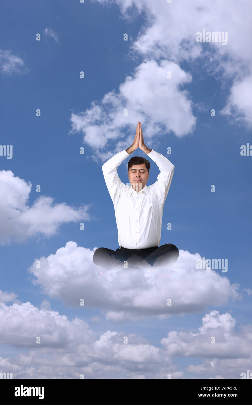 Geschäftsmann sitzt auf Wolken und praktiziert Yoga Stockfoto