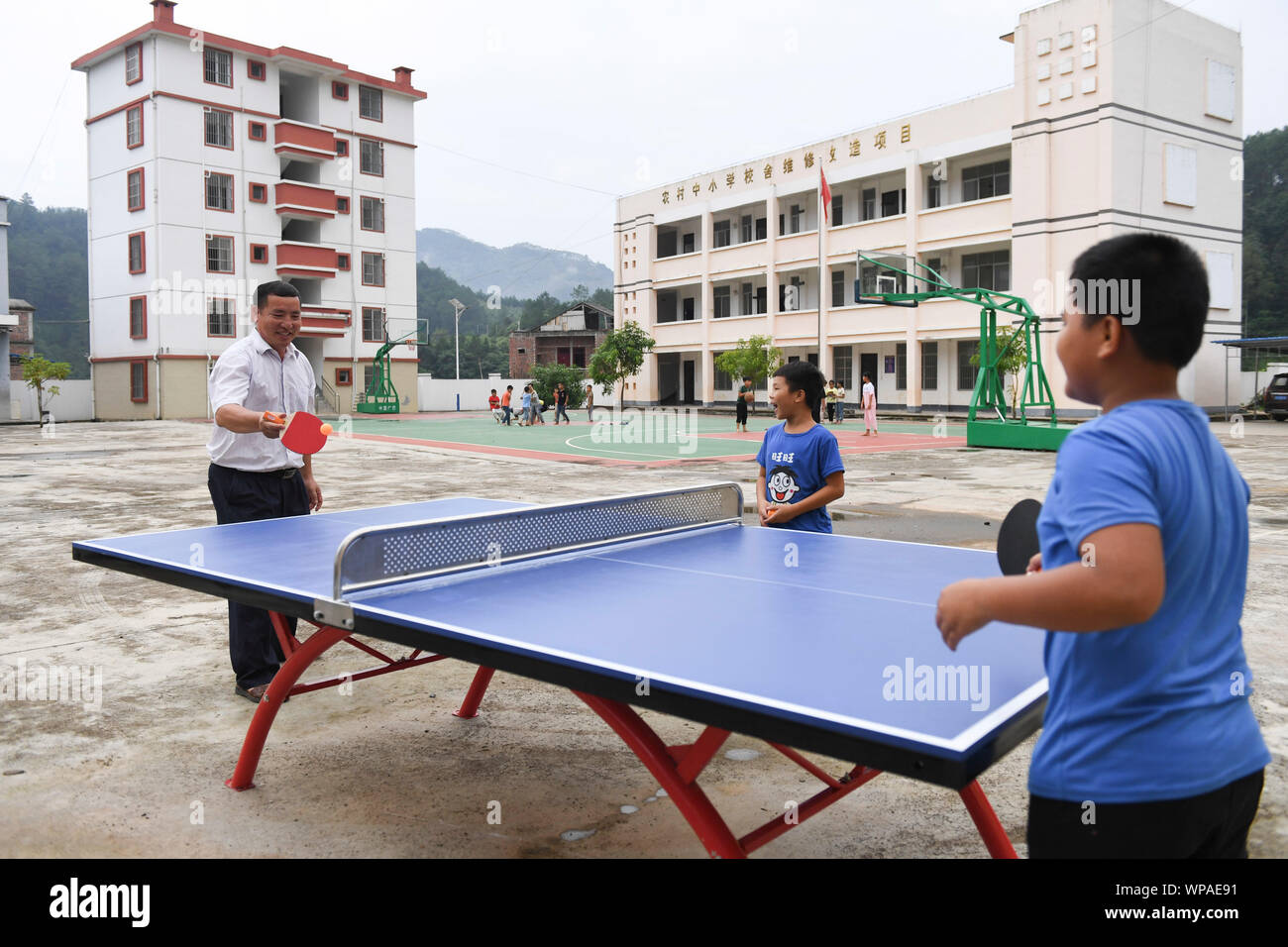 (190908) -- TIANDONG, Sept. 8, 2019 (Xinhua) - Wei Guoji spielt Ping - pong mit Studierenden an Tuogua Grundschule an Tuogua Dorf in Zuodeng Yao ethnischen Gemeinde Tiandong County, South China Guangxi Zhuang autonomen Region, Sept. 3, 2019. In den abgelegenen Bergen County, Tiandong Tuogua Grundschule ist über 60 km entfernt von der Kreisstadt, die nur noch mit einem robusten Mountain Road führen kann. Die 53-jährige Wei Guoji, ein Eingeborener ins Dorf, ist das Prinzip der Dorfschule. Wei wurde als Ersatz Lehrer der Schule nach Abschluss der Junior High School bei t eingestellt Stockfoto