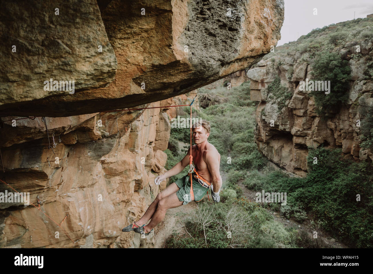 Ein junger Mann, der Kletterer, die auf einem überhängenden Route Stockfoto