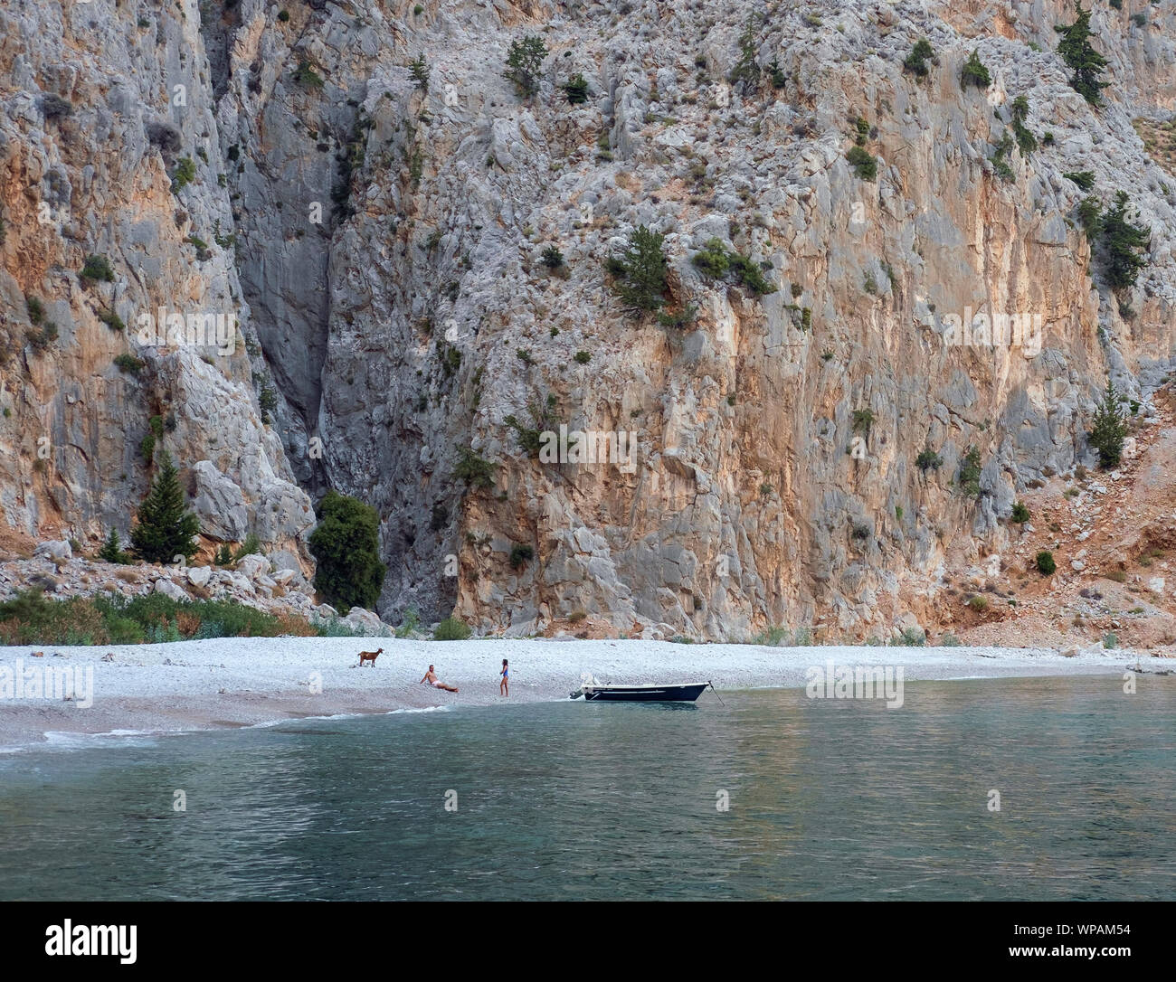 Insel Symi, Griechenland, August 2019. Blick auf die Bucht von Agios Georgios Strand. Zwei Personen und eine Ziege auf dem Strand. Stockfoto