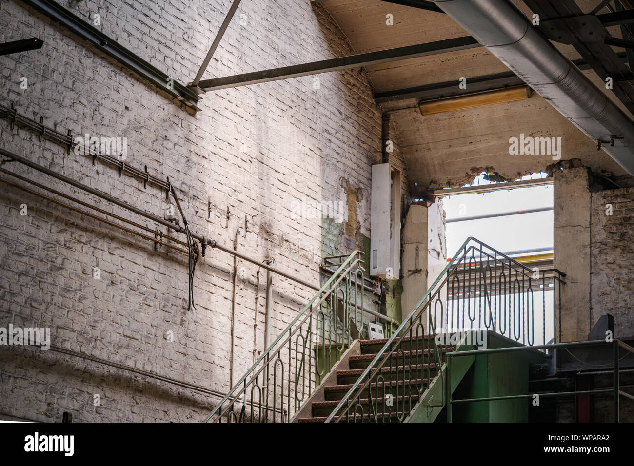 Innenansicht der Bohrung der Zerschlagung der Wand an der Oberseite der Stahltreppe in alten Backsteingebäude der ehemaligen Fabrik aufgeben oder industrielle Gebäude Stockfoto