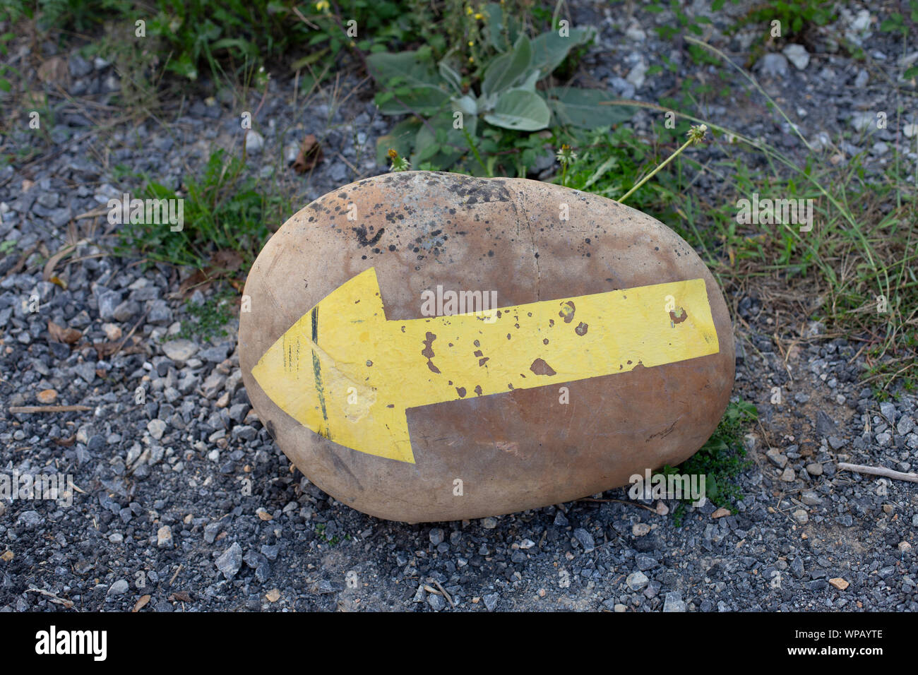 Nahaufnahme von Stein mit gelben Pfeil links, Camino de Santiago Stockfoto