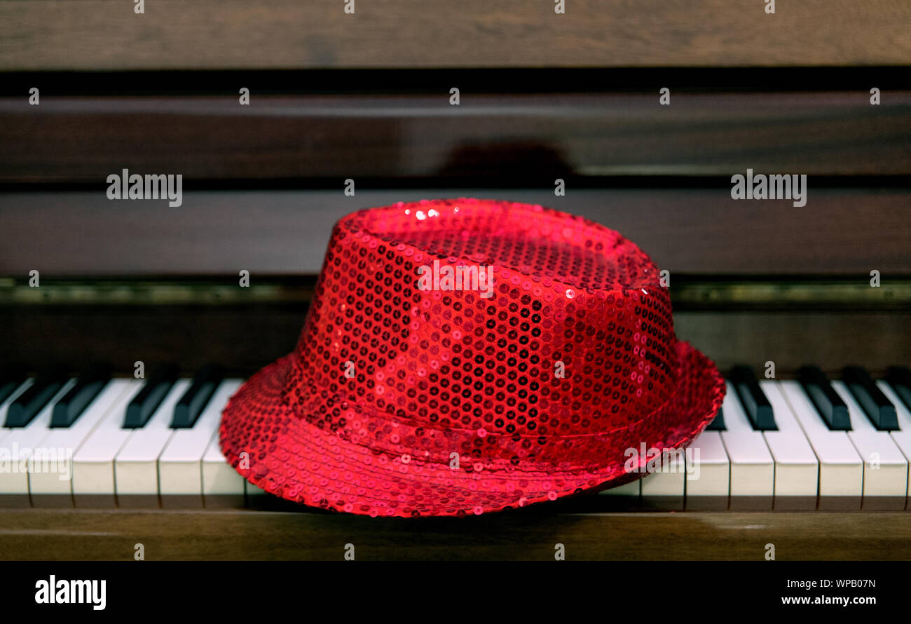 Eine rote paillette hat ist auf der Tastatur eines klassischen Piano links. Show business Konzept. Stockfoto