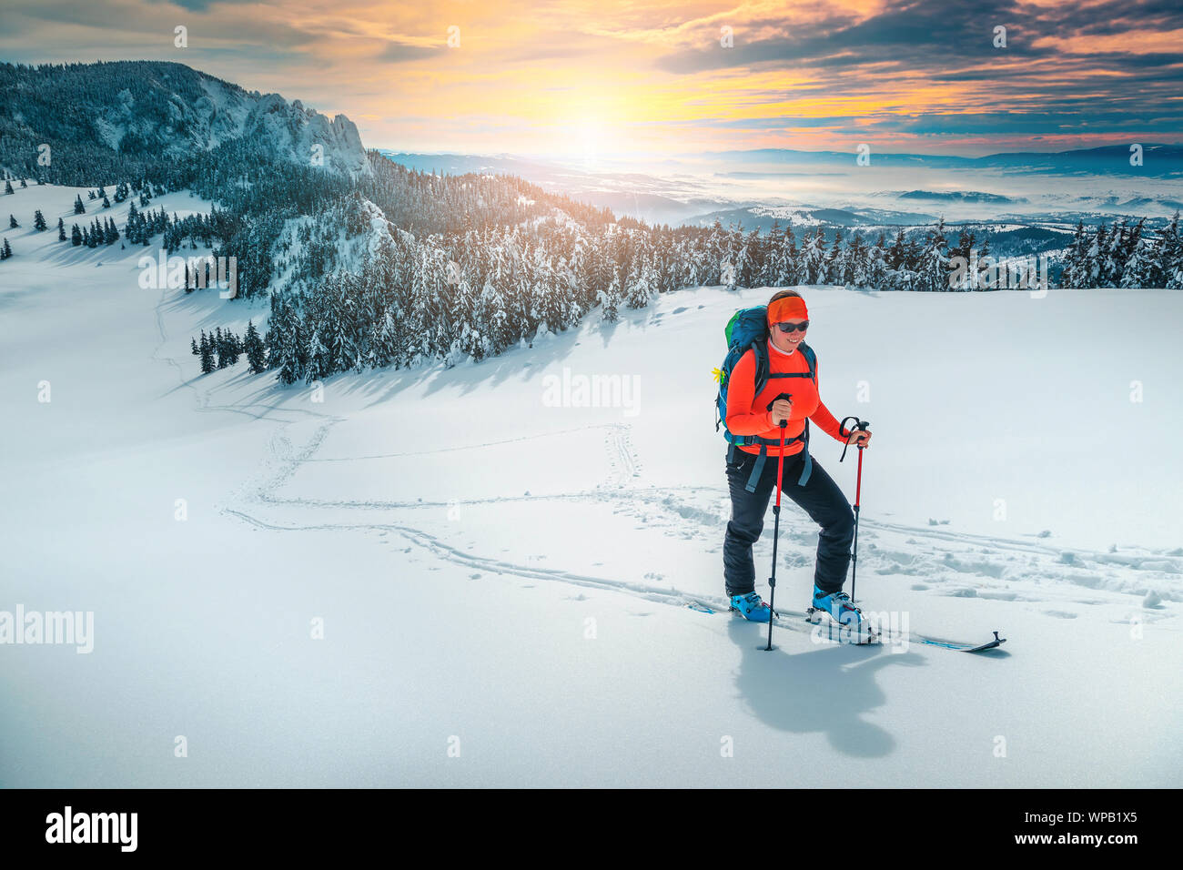 Freundliche backpacker Frau auf frischen Pulverschnee, Skitouren auf den verschneiten Pisten. Backcountry skier Frau mit bunten Rucksack und Mountain Equipment Stockfoto