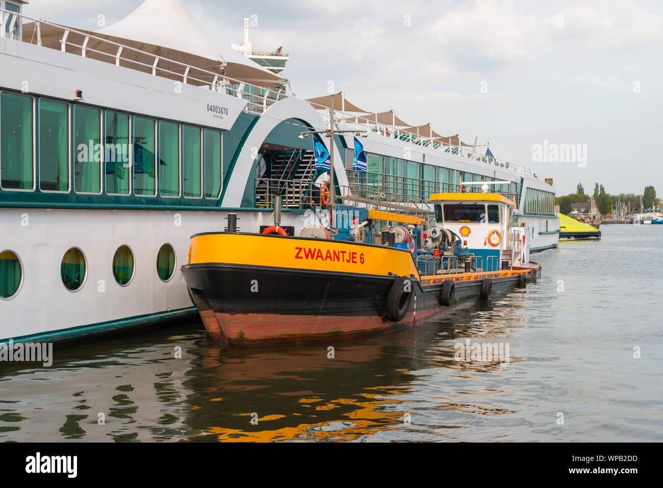 Amsterdam, Niederlande - 21 August 2019: Rhein Kreuzfahrtschiff durch ein Boot in der niederländischen Hafen von Amsterdam betankt werden Stockfoto