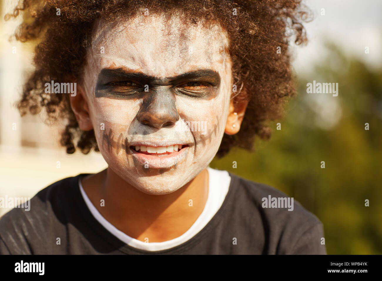 Kopf und Schultern Portrait von harten Afrikaner - Junge tragen Skelett Kostüm posiert im Freien auf Halloween, beleuchtet durch Sonnenlicht Stockfoto