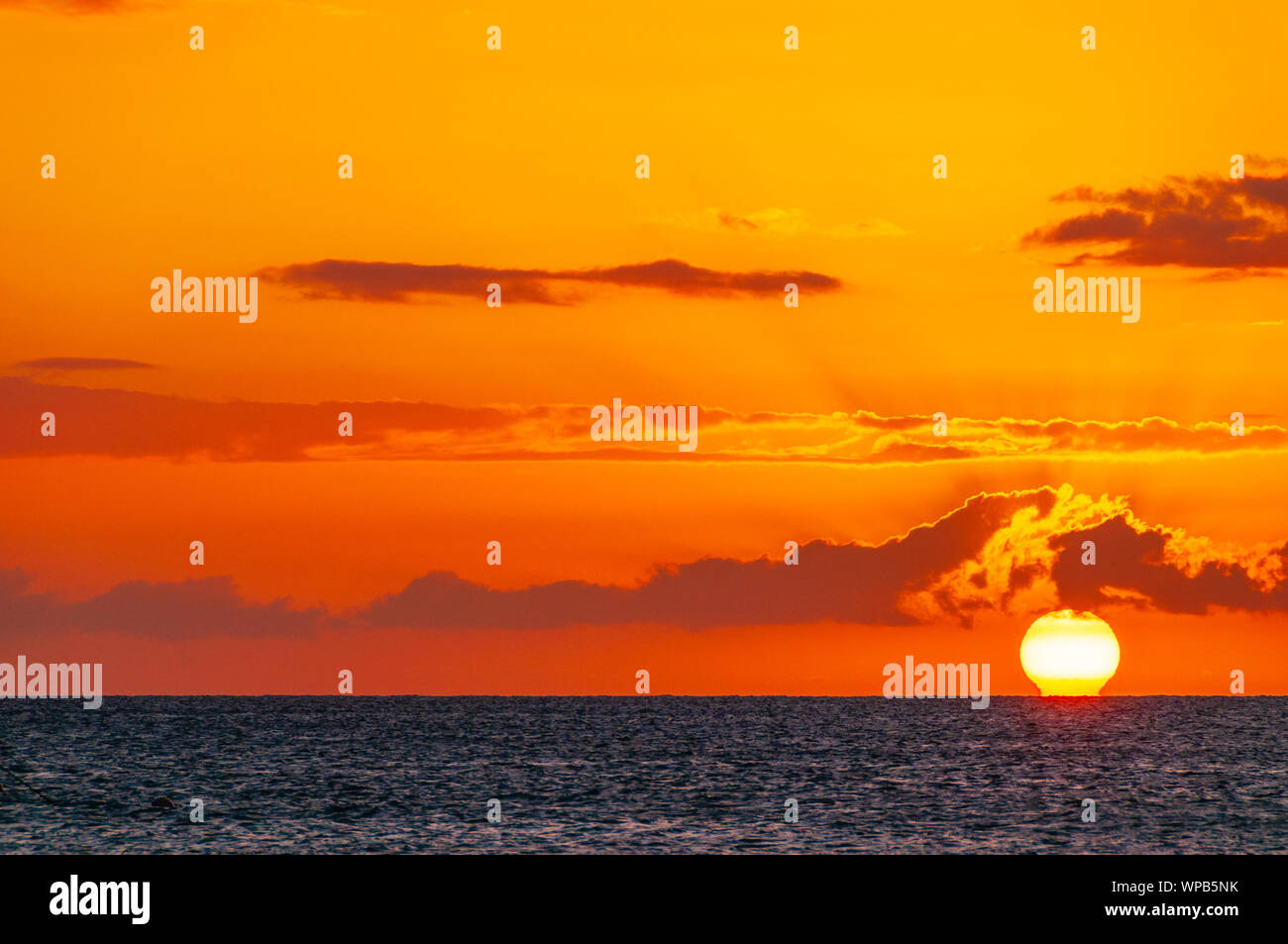 Schöne große rote Sonnenuntergang über dem Pazifischen Ozean hinter bunten Wolken auf Maui, Hawaii, USA Stockfoto