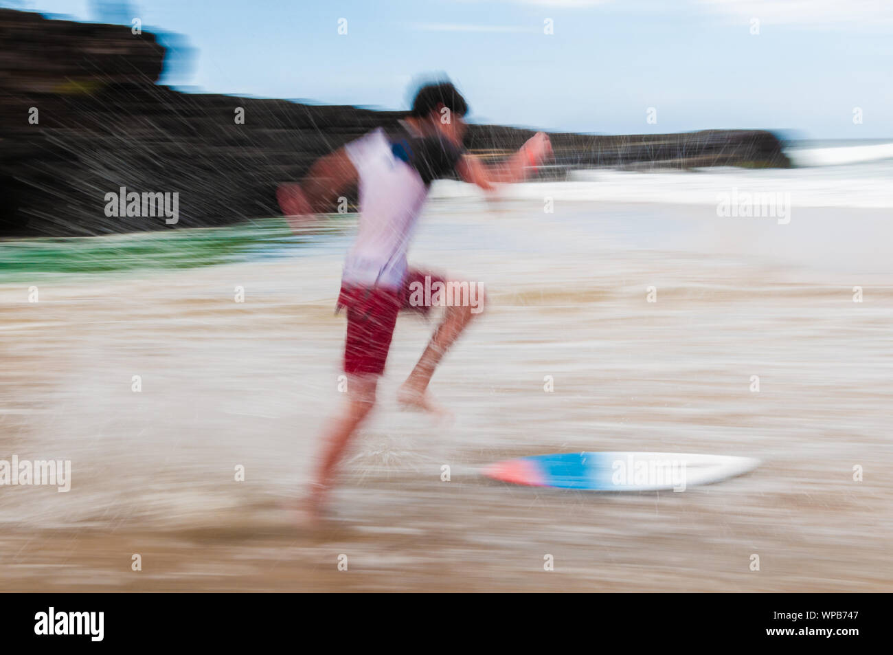 Junger Mann laufen und springen auf einem skim Board im flachen Wasser am Strand auf Maui, Hawaii, USA Stockfoto