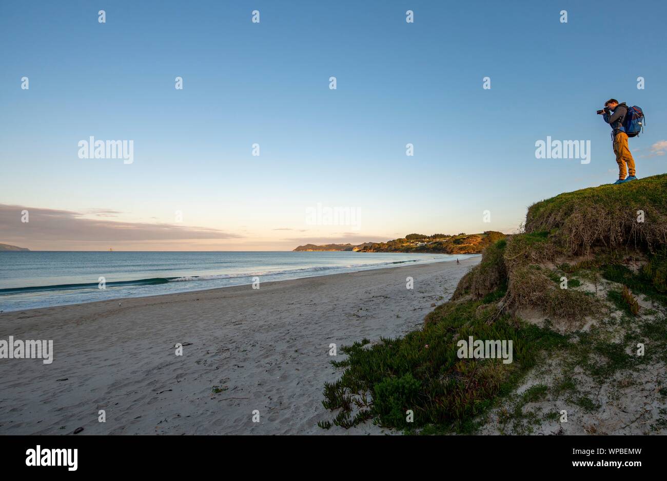 Junger Mann fotografieren, waipu Strand bei Sonnenuntergang, waipu Cove, Northland, Neuseeland Stockfoto