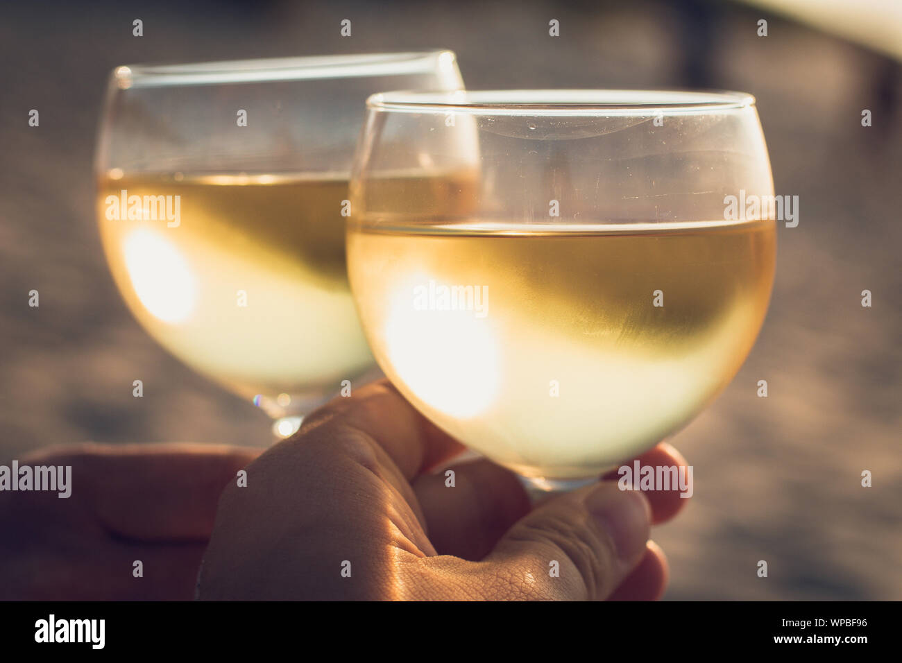 Zwei Leute trinken kalten weißen Wein am Strand bei Sonnenuntergang Stockfoto