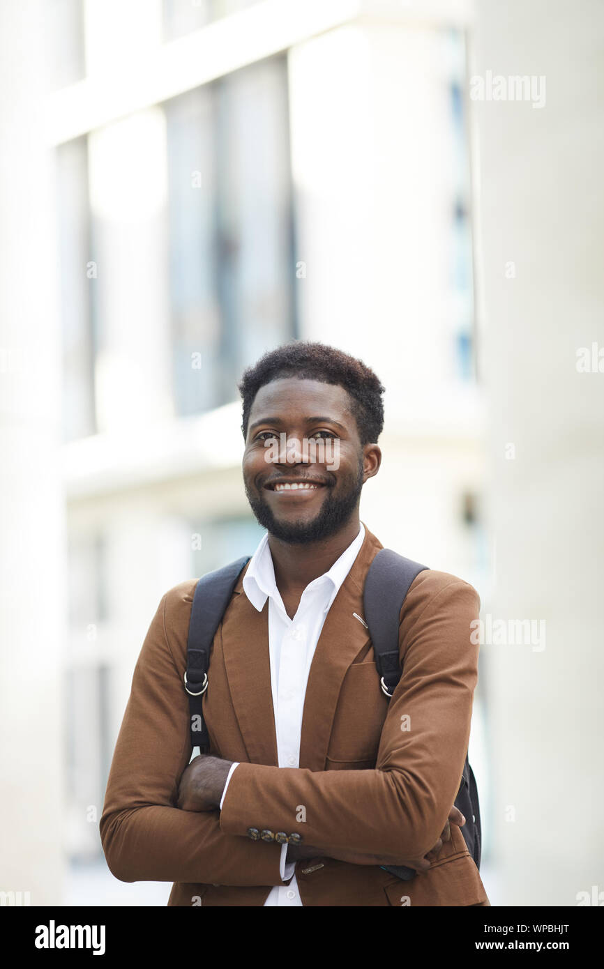 Taille bis Portrait von zuversichtlich Afrikaner Mann lächelt glücklich an Kamera und stehen mit den Armen in der Stadt Straße überquert, kopieren Raum Stockfoto