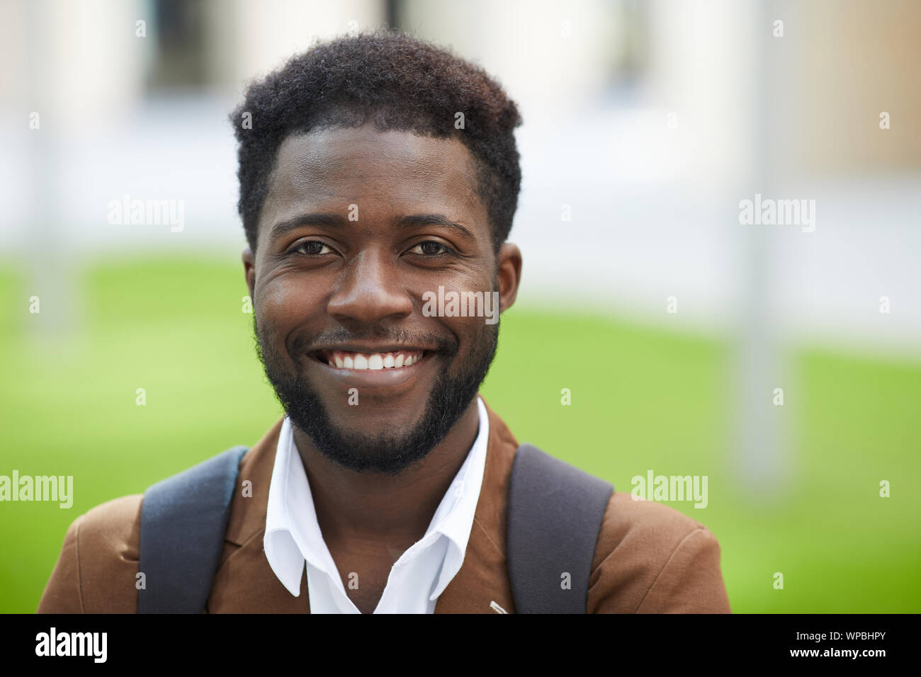 Kopf und Schultern Portrait von stattlichen Afrikaner Mann lächelt glücklich an Kamera und posiert im Freien in Straße, Platz kopieren Stockfoto