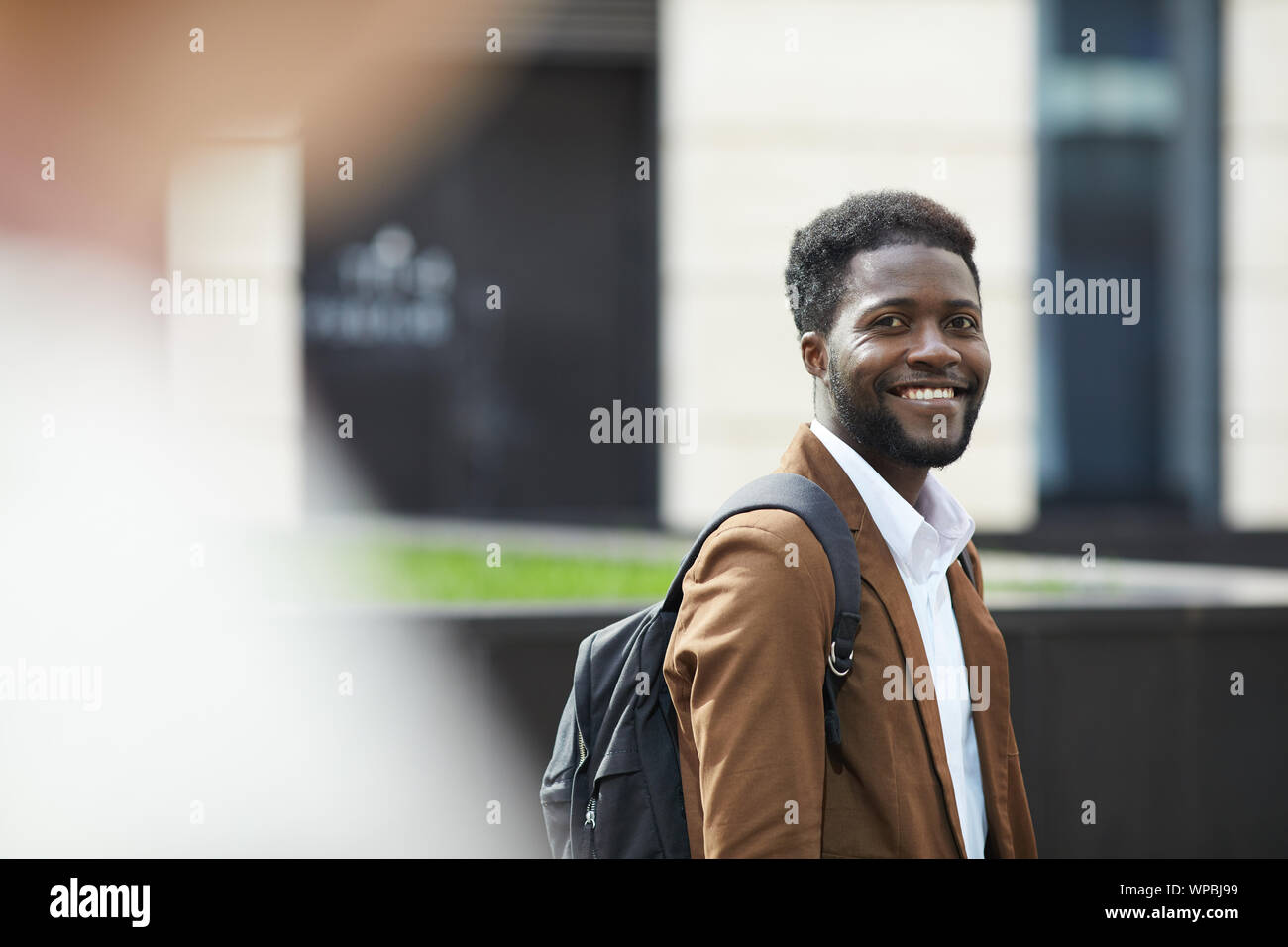 Taille bis Porträt der jungen Afrikaner Mann lächelt glücklich an Kamera beim Stehen im Freien ion Stadt Straße, Platz kopieren Stockfoto