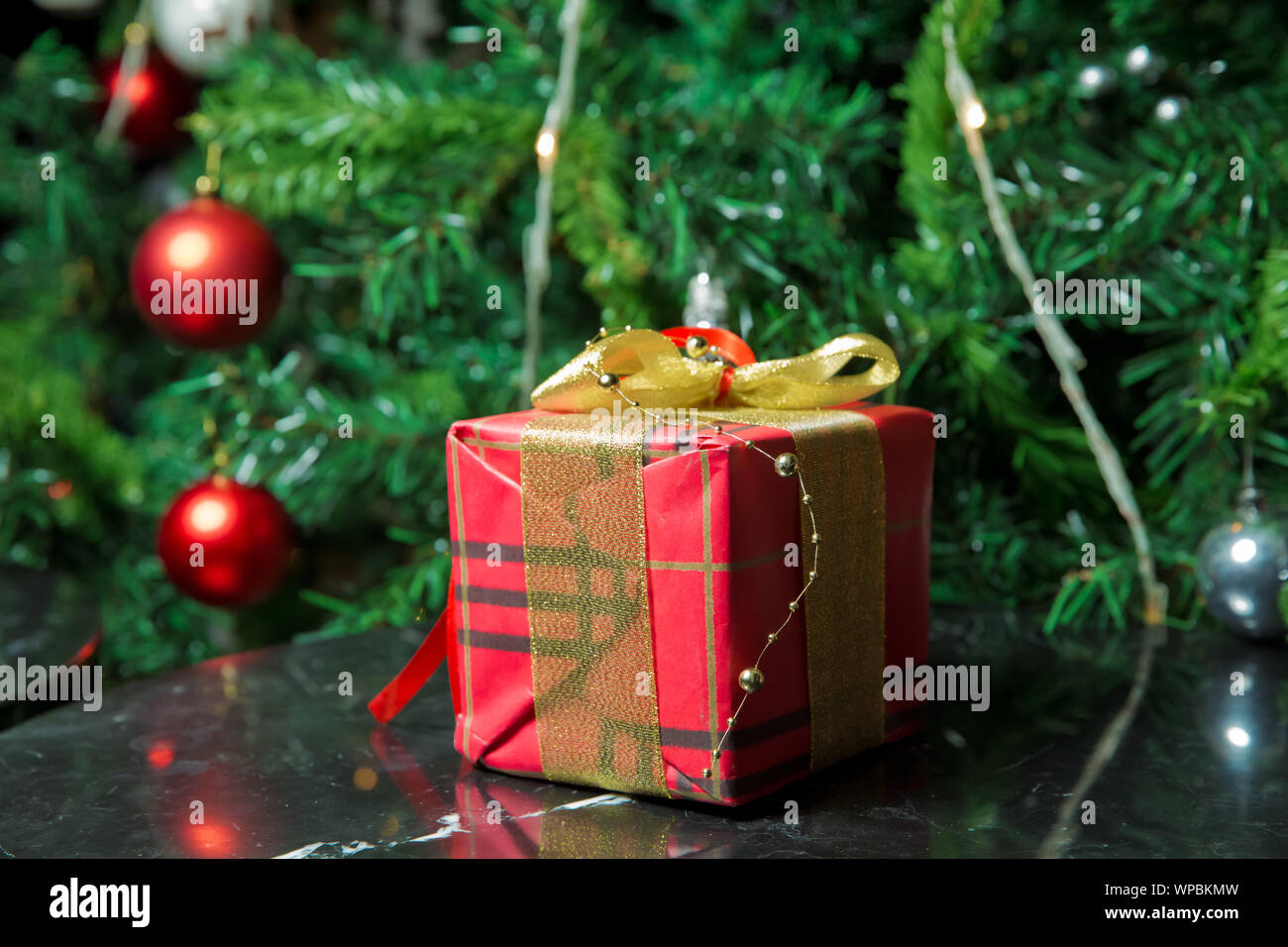 Geschenke unter dem Weihnachtsbaum mit golg Band und Schleifchen verziert. Rot Weihnachtsgeschenk. Schöne Weihnachten Baum mit roten Kugeln. Stockfoto