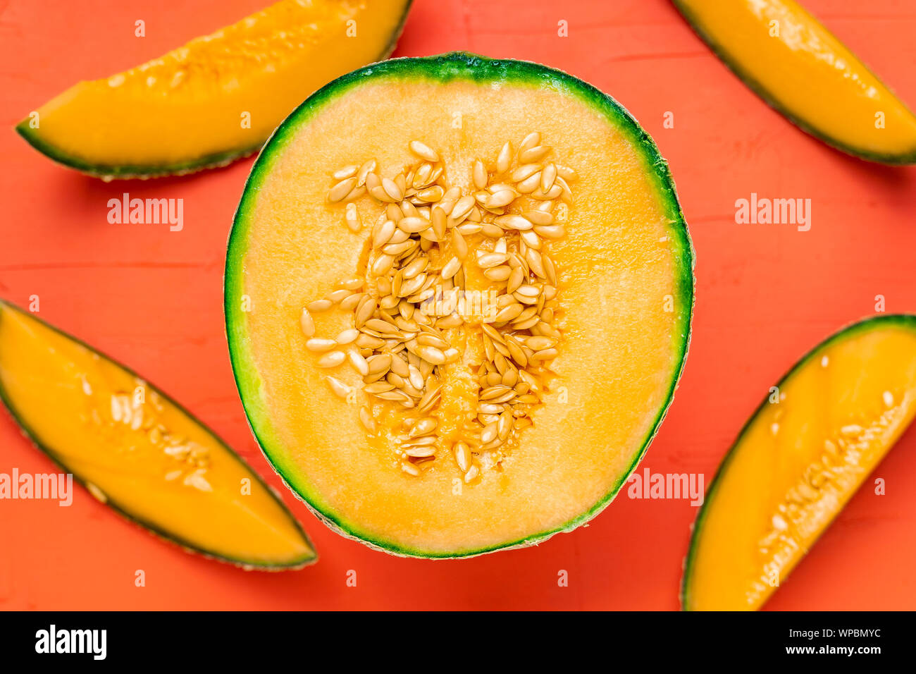 Ansicht von oben Nahaufnahme eines frisch geschnittenen Melone auf eine Koralle rote Farbe Hintergrund. Sommer Obst essen Fotografie. Stockfoto