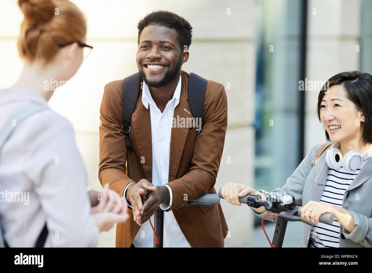 Gruppe der zeitgenössischen jungen Menschen in Stadt Straße chatten, auf Afrikaner - Mann glücklich lächelnd, kopieren Raum konzentrieren Stockfoto