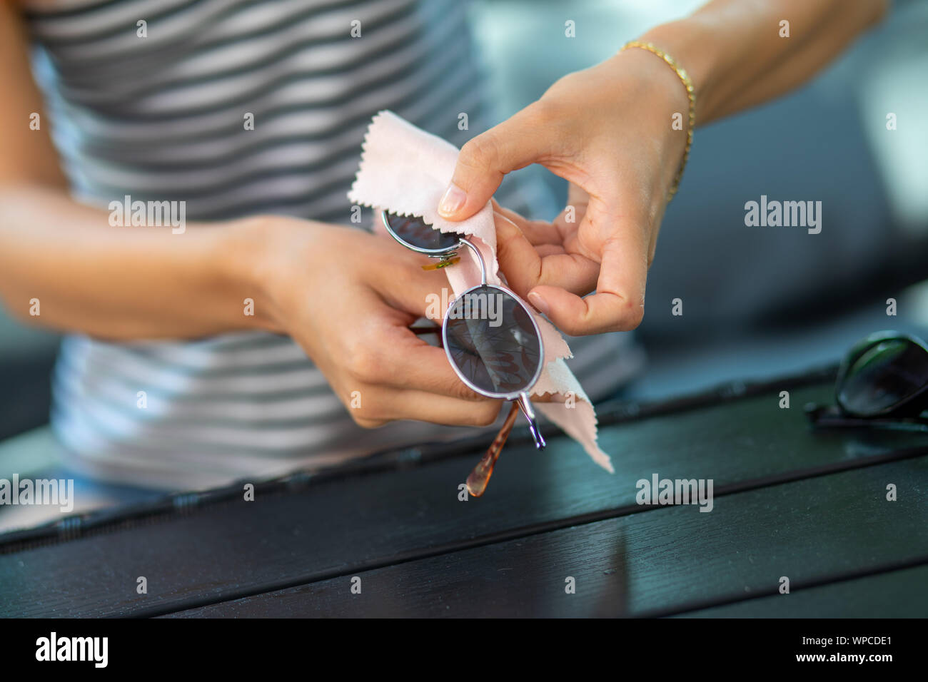 Frau Hände Reinigung Ihrer Sonnenbrille mit Mikrofasertuch wischen, wischen Sonnenbrille Stockfoto