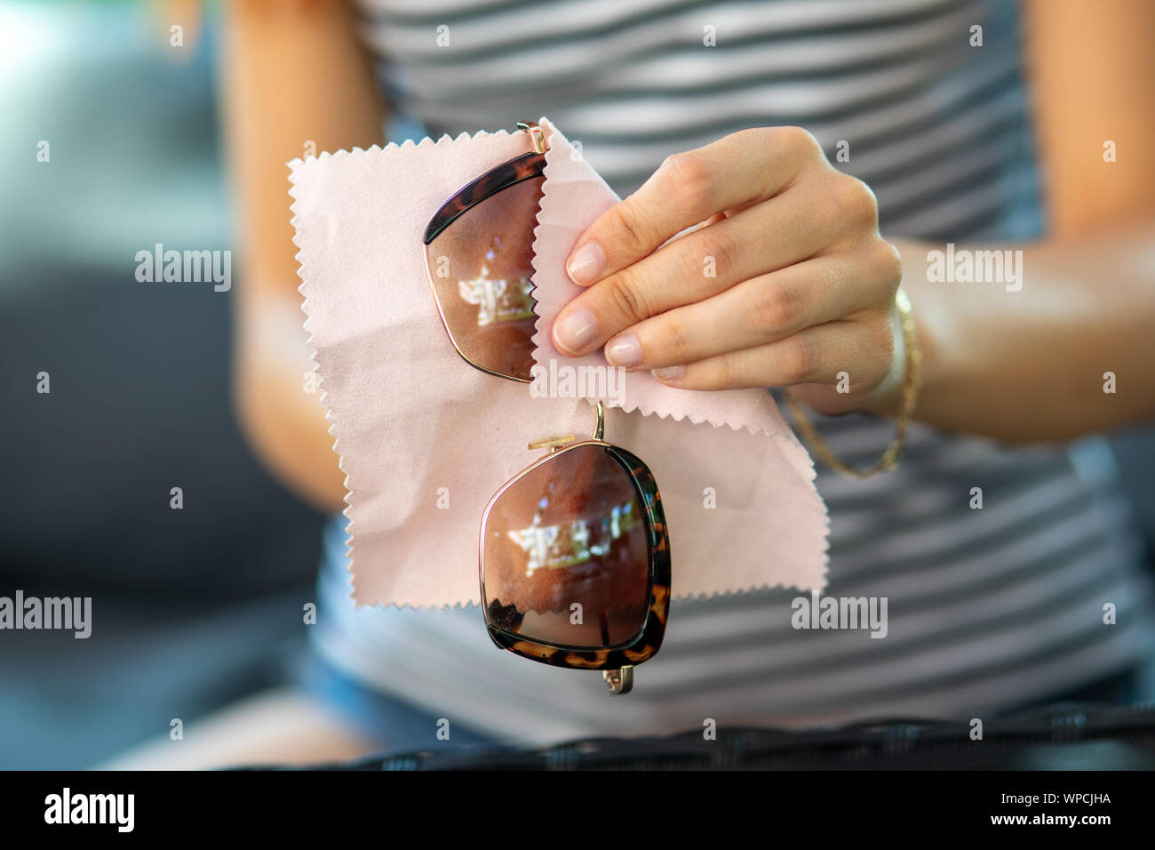 Frau Hände Reinigung Ihrer Sonnenbrille mit Mikrofaser Tuch abwischen, Unmengen Sonnenbrille Stockfoto