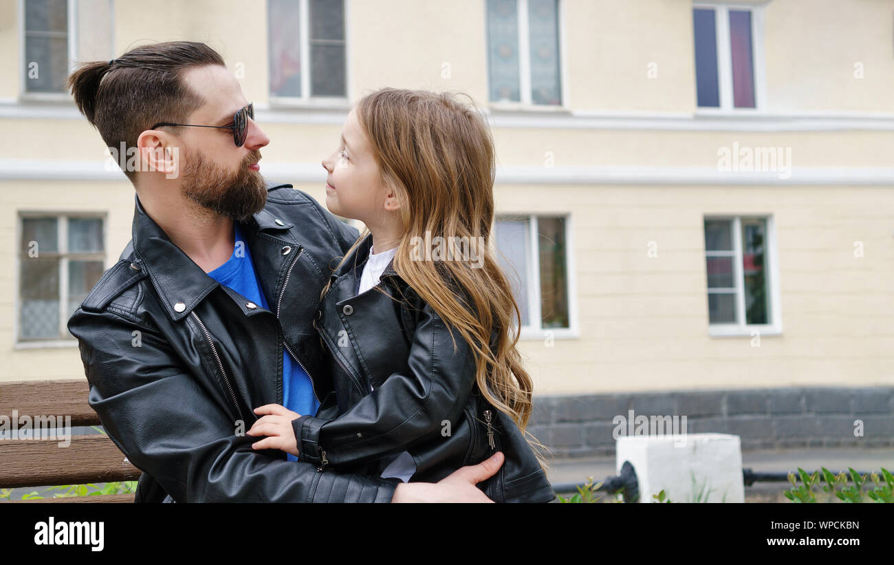 Modische stilvolle Familie für einen Spaziergang. Glück, ein Elternteil sein. Charmante kleine Tochter sitzt auf dem Schoß ihres Vaters. Ein vertrauliches Gespräch. F Stockfoto