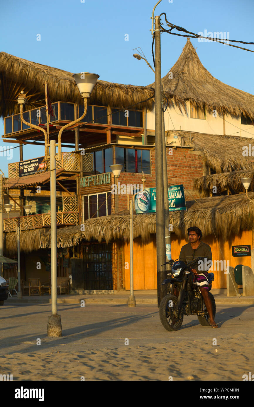 MANCORA, PERU - 20. AUGUST 2013: Unbekannter junger Mann auf dem Motorrad beobachten, die untergehende Sonne und Strand am 20. August 2013 in Mancora, Peru. Stockfoto